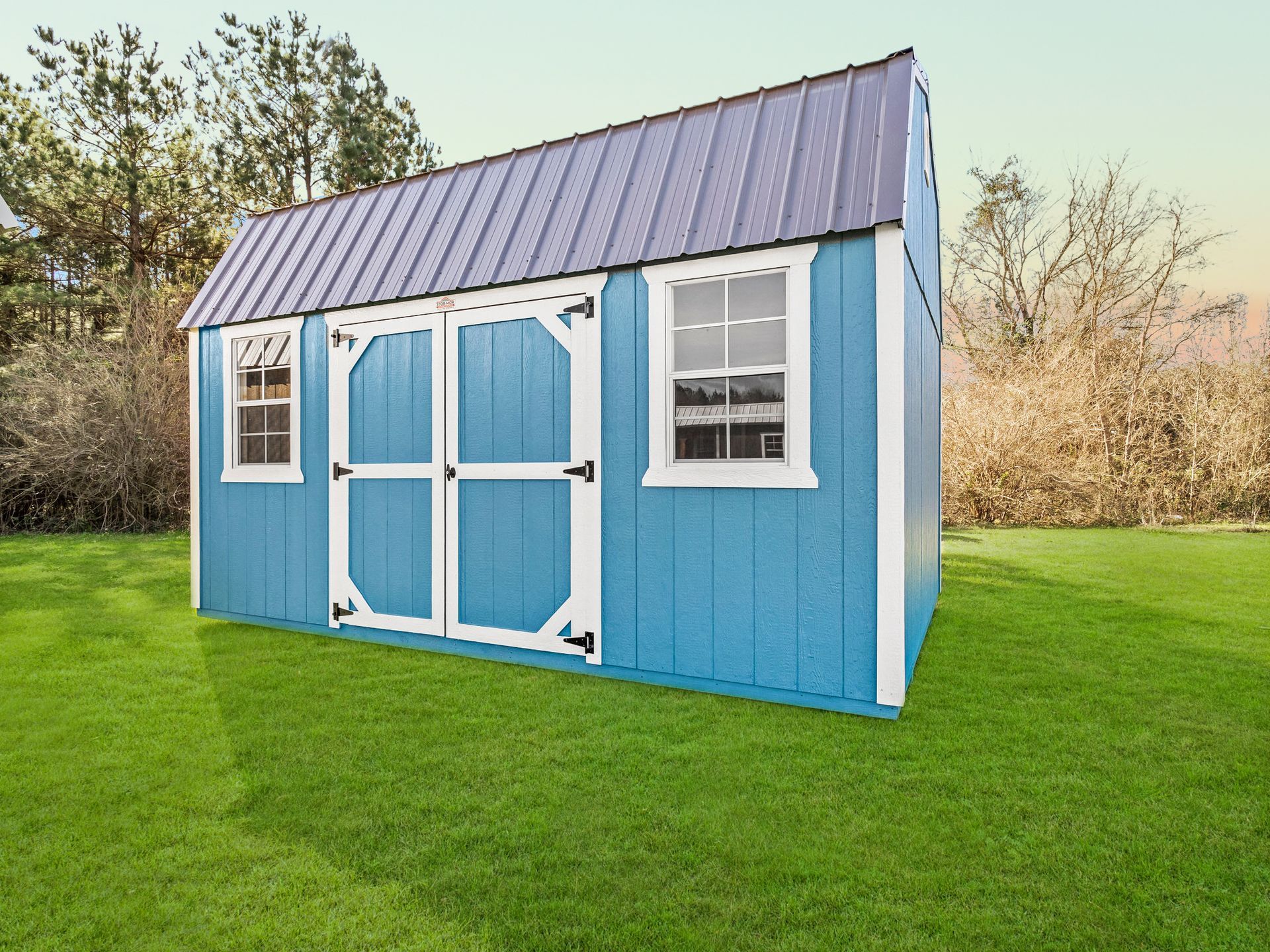 Superior Outdoor Centers Lofted Barn A blue and white shed is sitting on top of a lush green lawn.