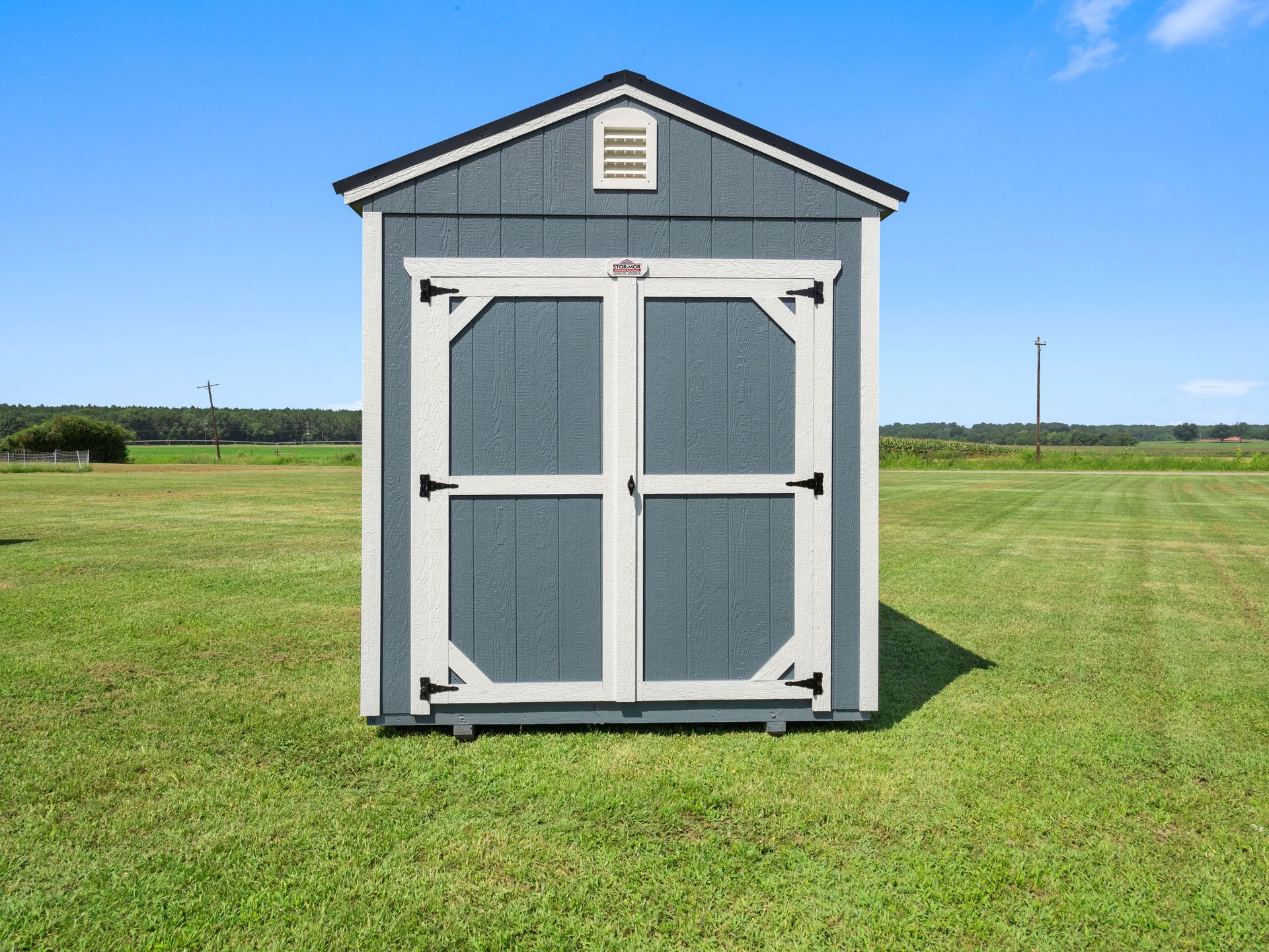 Superior Outdoor Centers Utility Shed A small shed is sitting in the middle of a grassy field.