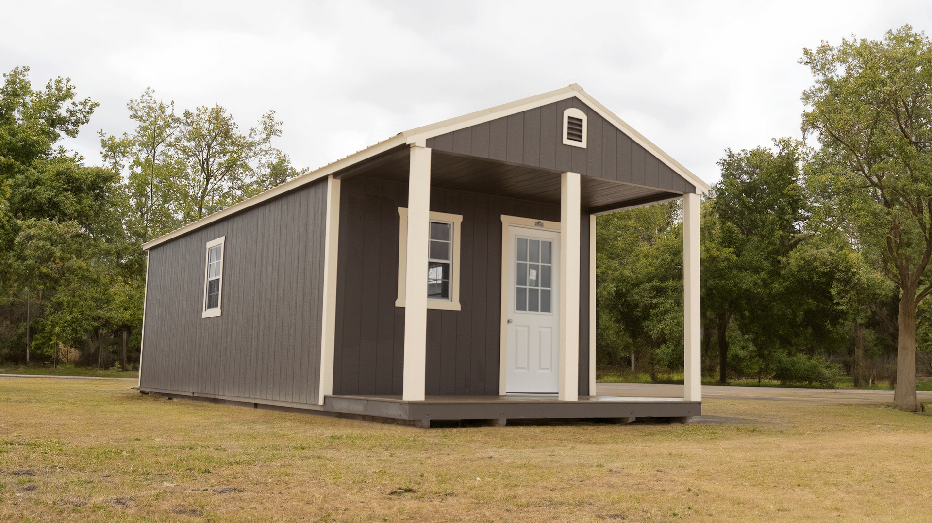 Superior Outdoor Centers  cabin portable A small house with a porch is sitting in the middle of a field.