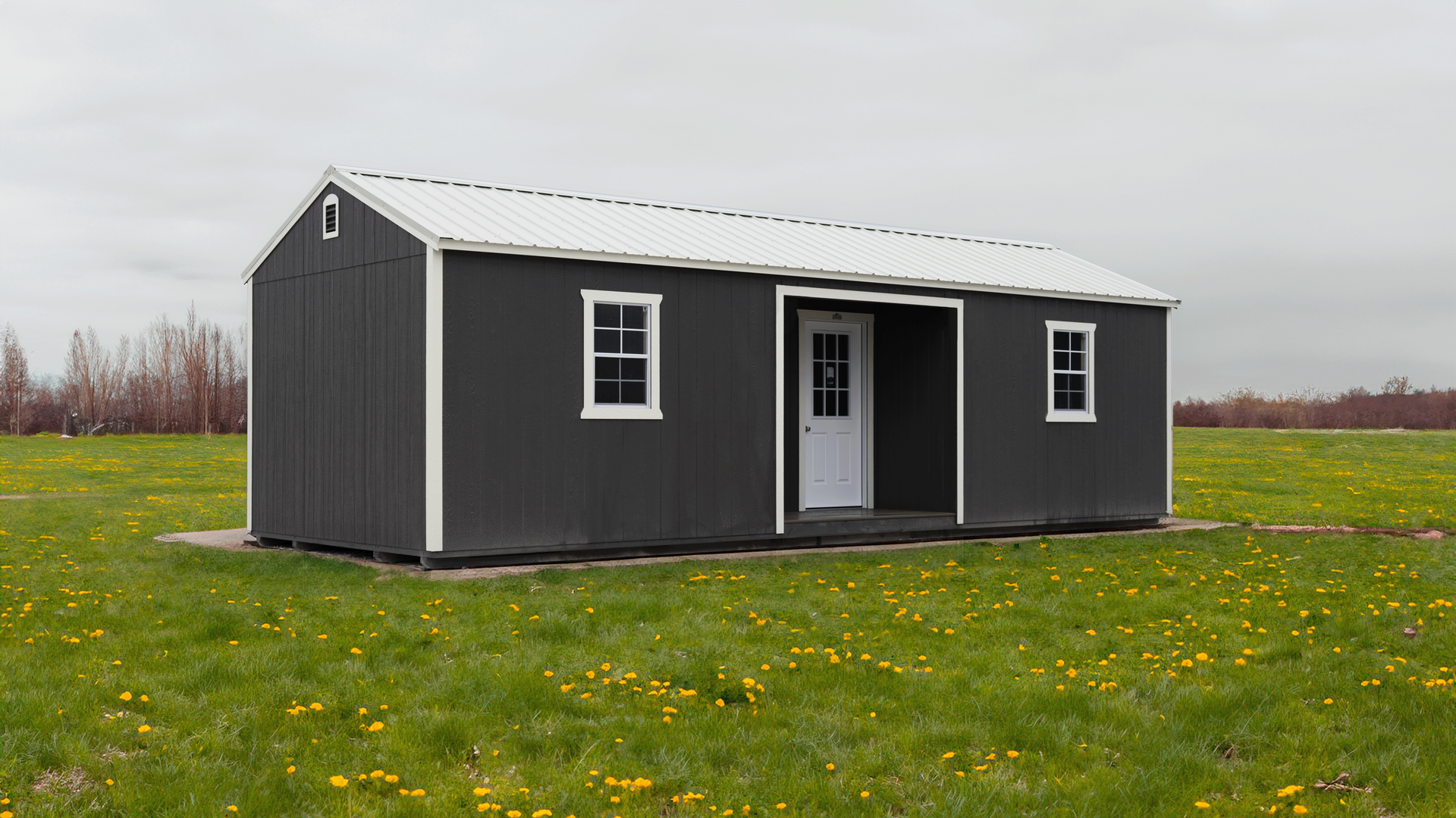 Superior Outdoor Centers  center cabin A small black and white shed is sitting in the middle of a grassy field.