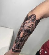 Arm tattoo of a robed classical figure in black and gray ink on a forearm
