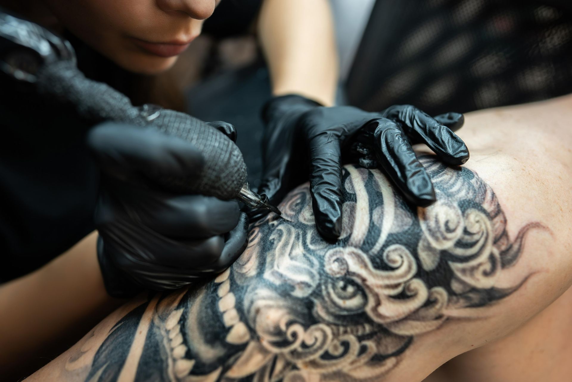 Tattoo Artist With Black Gloves Using A Tattoo Machine, Inking A Detailed Design — Tattoo Inc Studio in Surfers Paradise, QLD