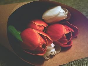 Assorted colorful flowers in a dark bowl on a brown surface