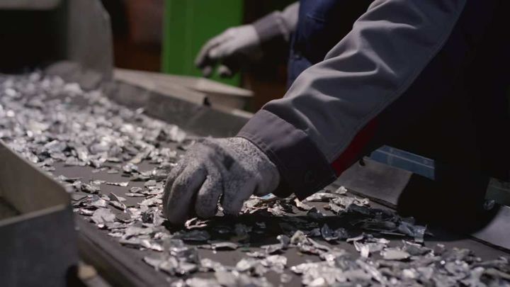 Worker sorts trash on conveyor belt at waste recycling plant