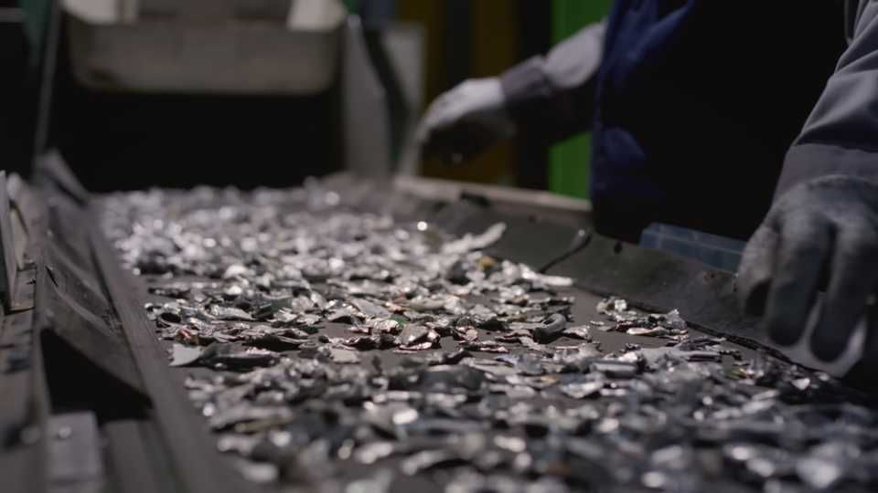 Worker sorts trash on conveyor belt at waste recycling plant