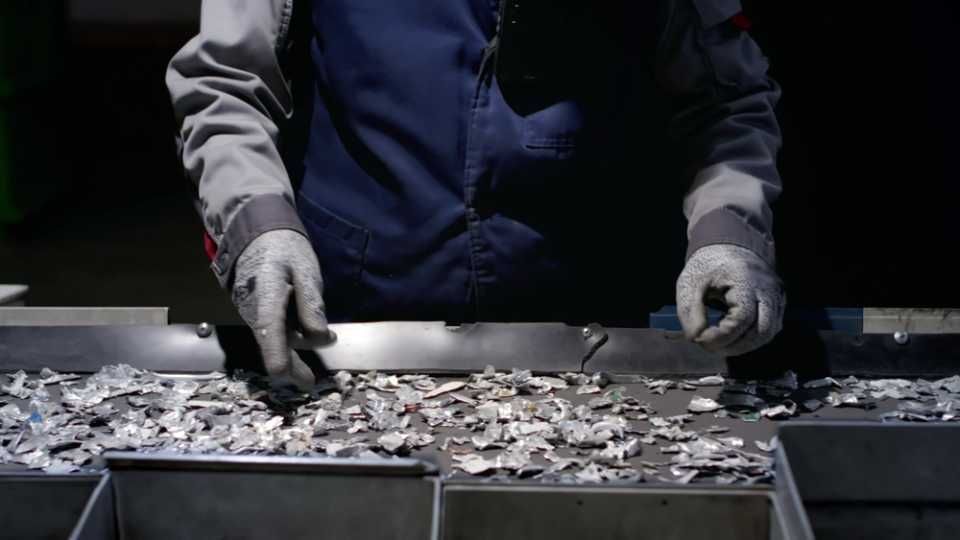 Worker sorts trash on conveyor belt at waste recycling plant