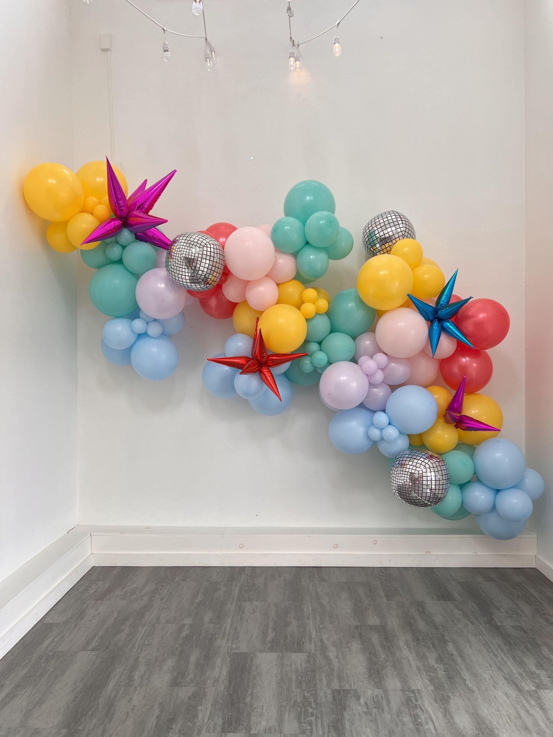 a bunch of balloons are hanging on a wall in a room