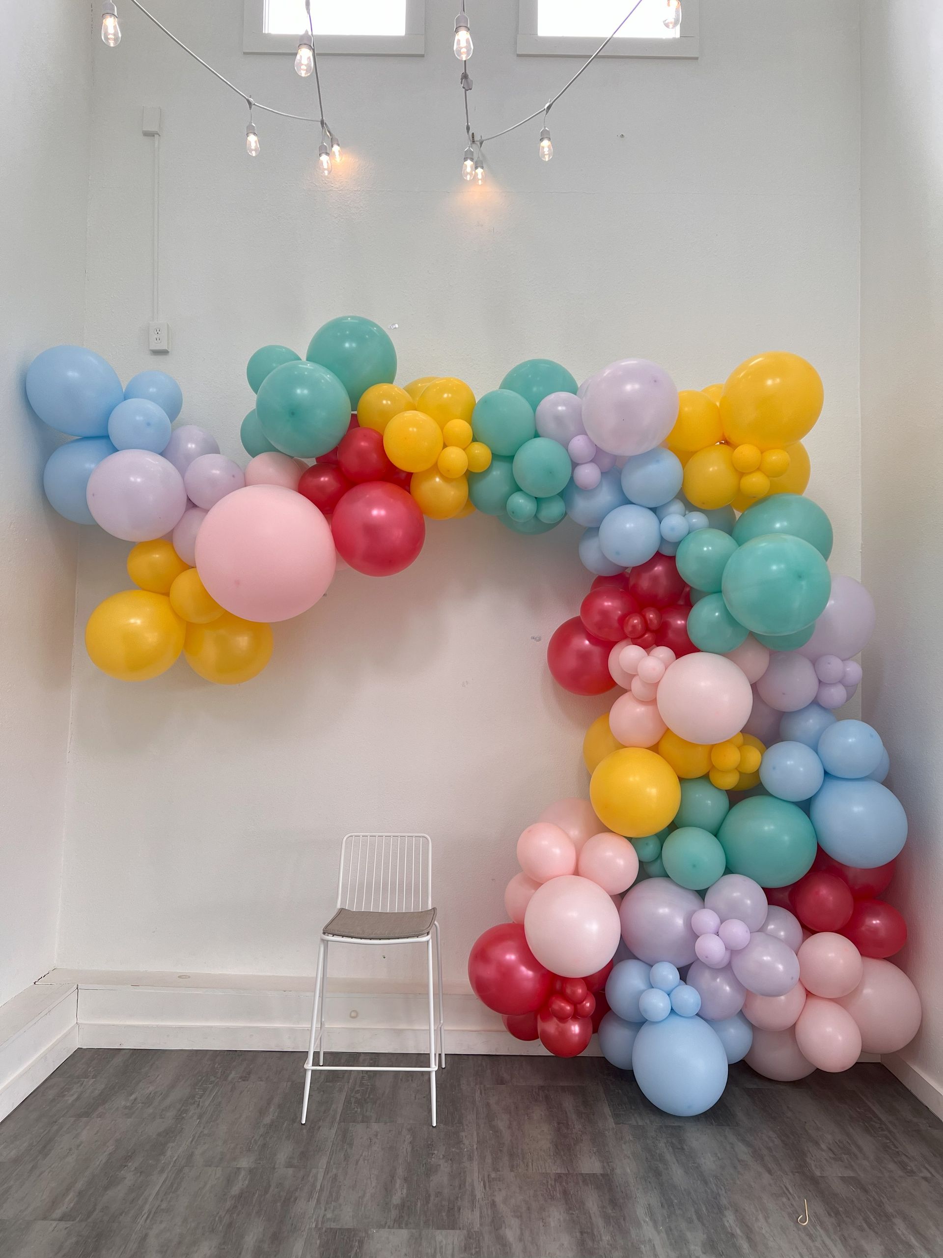 a room filled with lots of colorful balloons and a chair