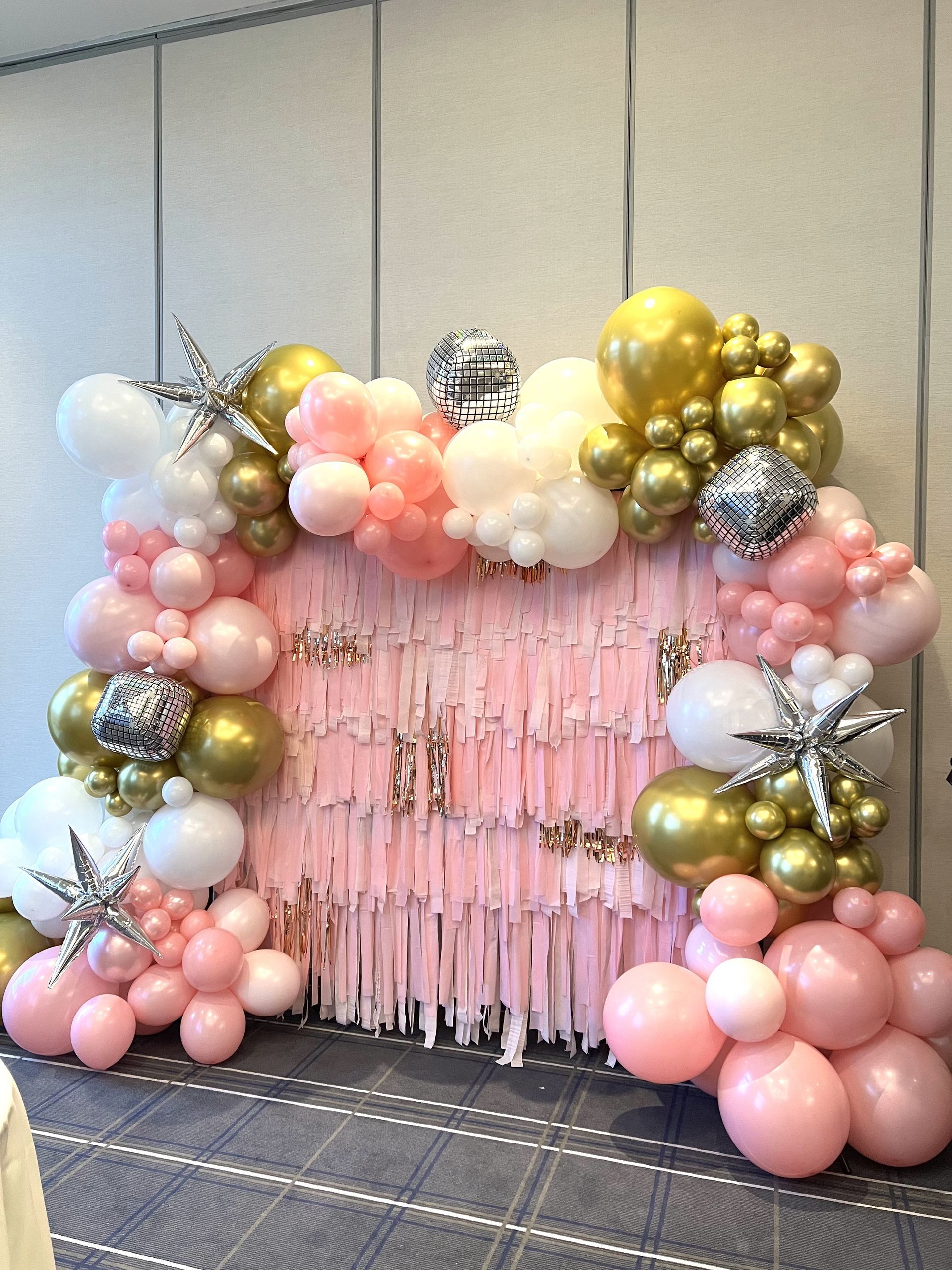 Gold, pink, and white balloon garland forming an arch against a backdrop
