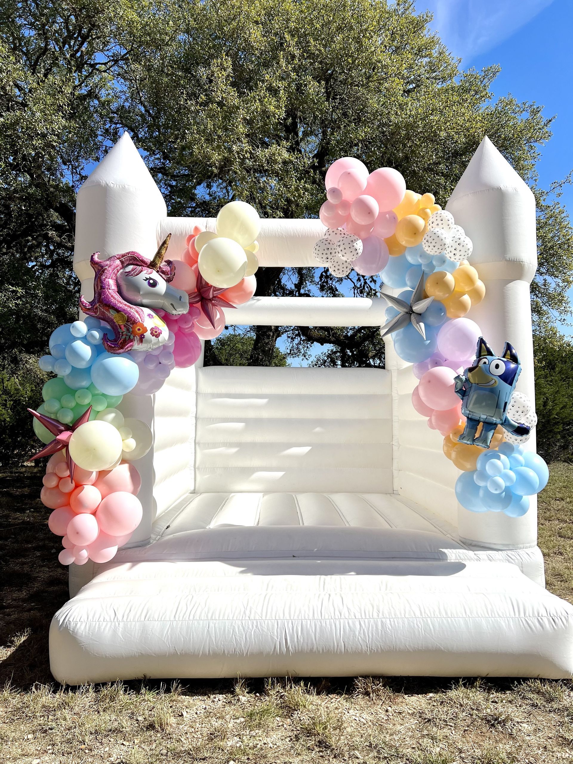 a white bouncy castle decorated with balloons and a unicorn