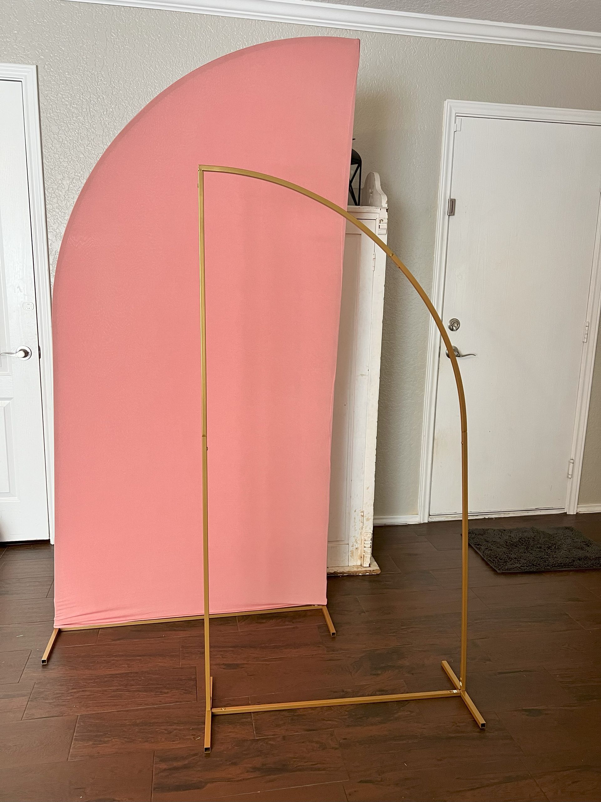 a pink backdrop is sitting on a wooden floor next to a gold frame