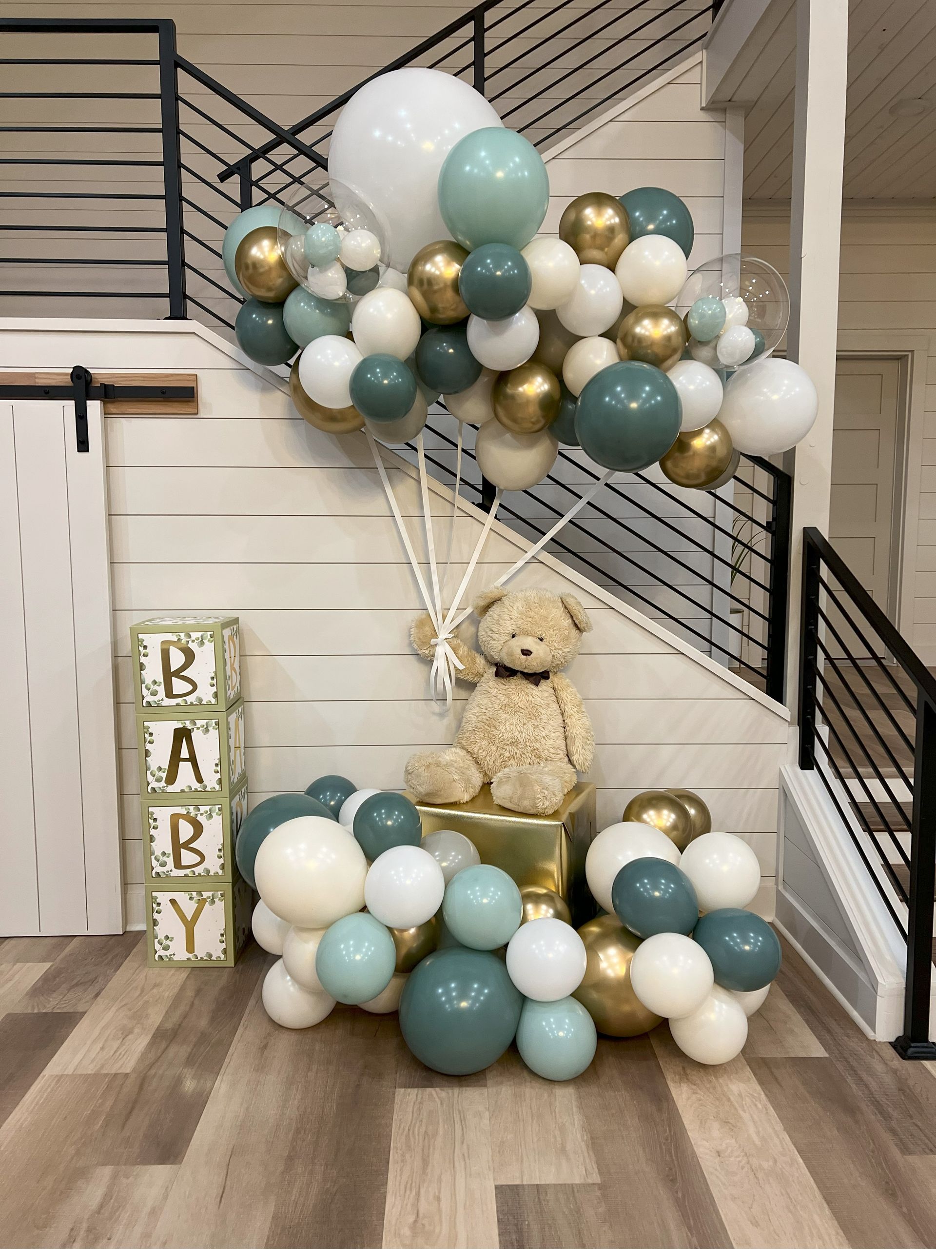 a teddy bear is sitting on a box surrounded by balloons