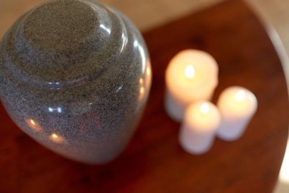 urna cineraria grigia e candele accese