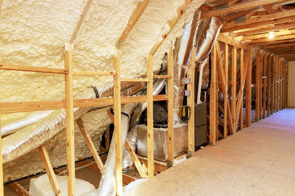 Insulated attic with exposed wooden framing and ductwork along the roofline