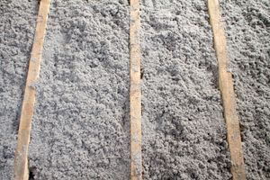 Three parallel wooden beams framing gray, fluffy insulation material