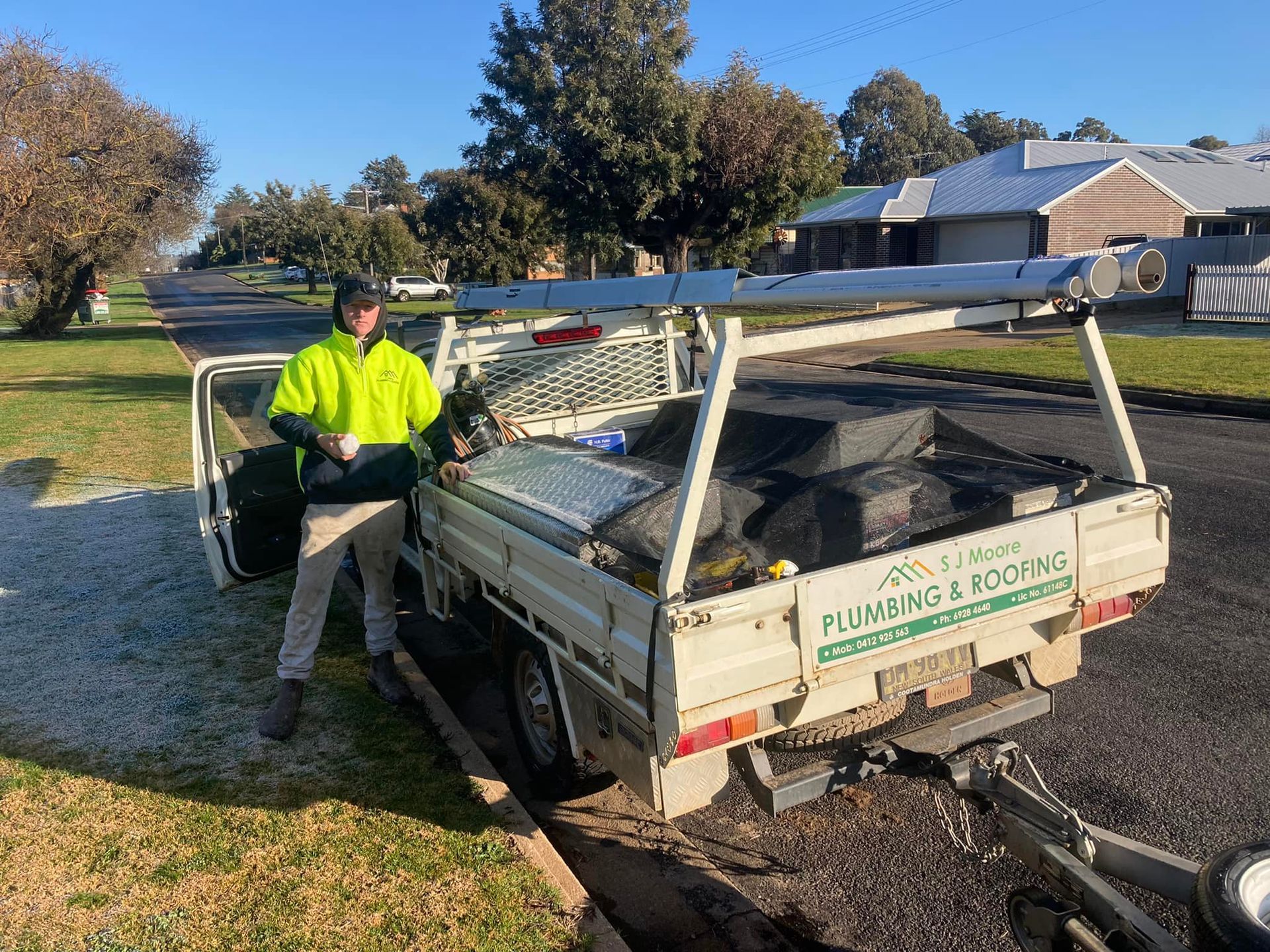 Worker In Neon Jacket Beside A Landscaping Trailer — SJ Moore Plumbing & Roofing in Wagga Wagga, NSW