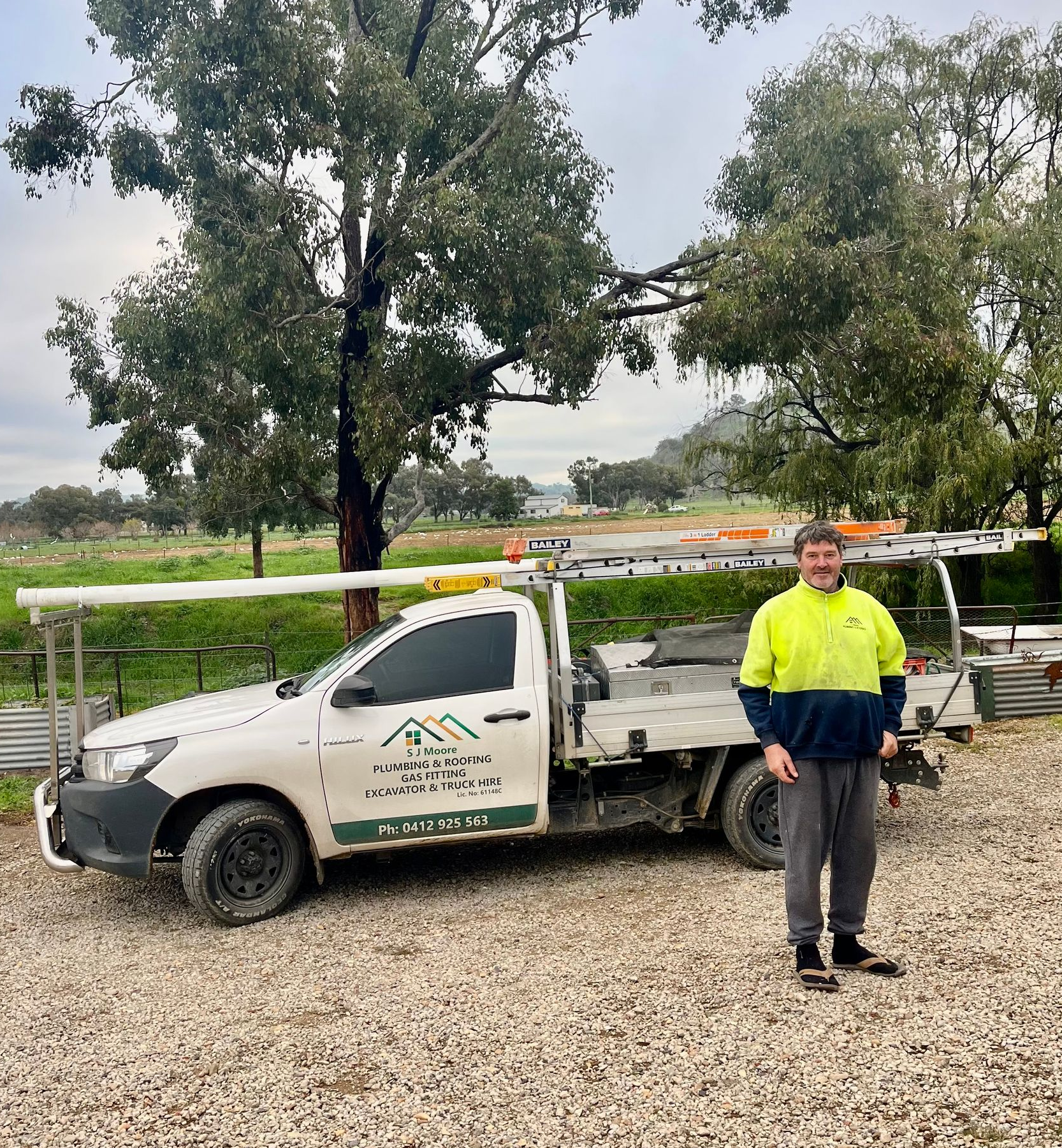 Four crew members stand in front of a white utility truck with roof-mounted pipes outdoors - SJ Moore Plumbing & Roofing in Wagga Wagga, NSW