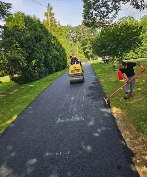 Professional applying asphalt sealcoating to driveway surface for protection and enhanced durability
