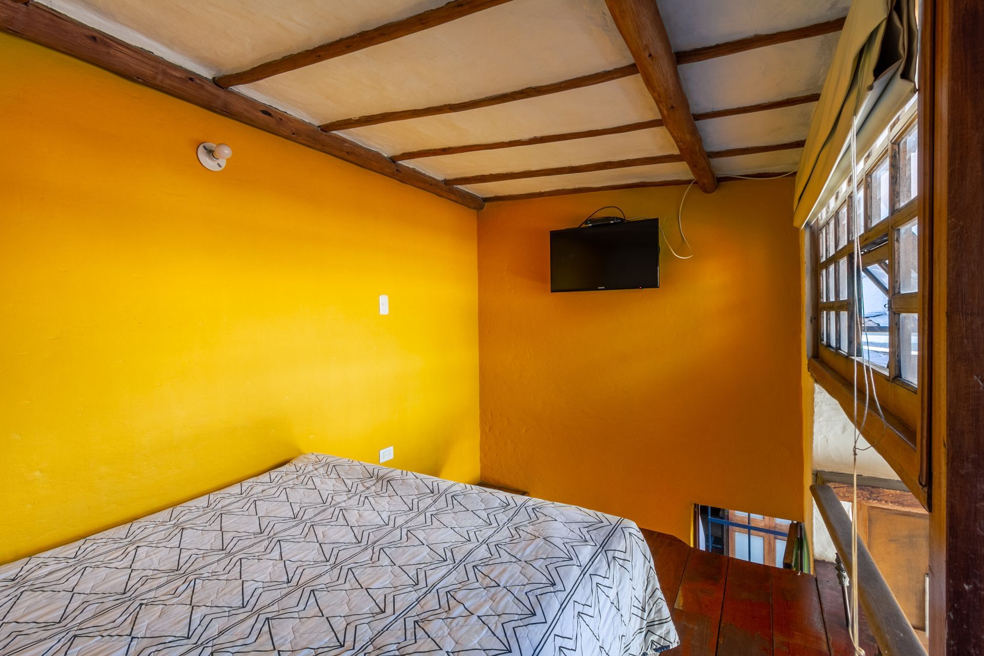 A bedroom with a bed and a television on the wall.