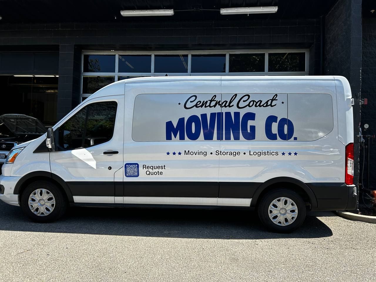 White Central Coast Moving Co. van parked outside a garage, side view