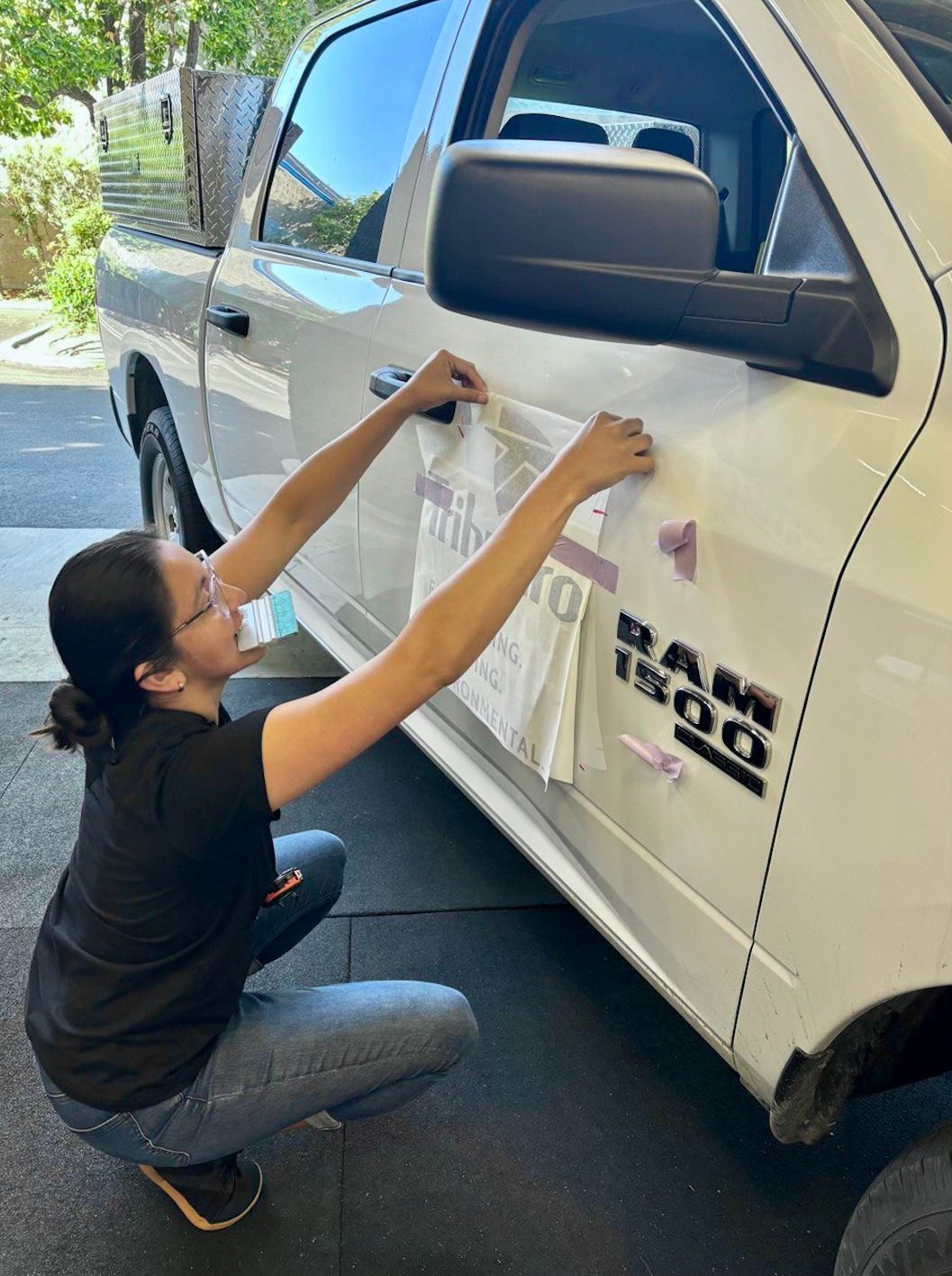 Person applying decals to the side of a white truck outdoors