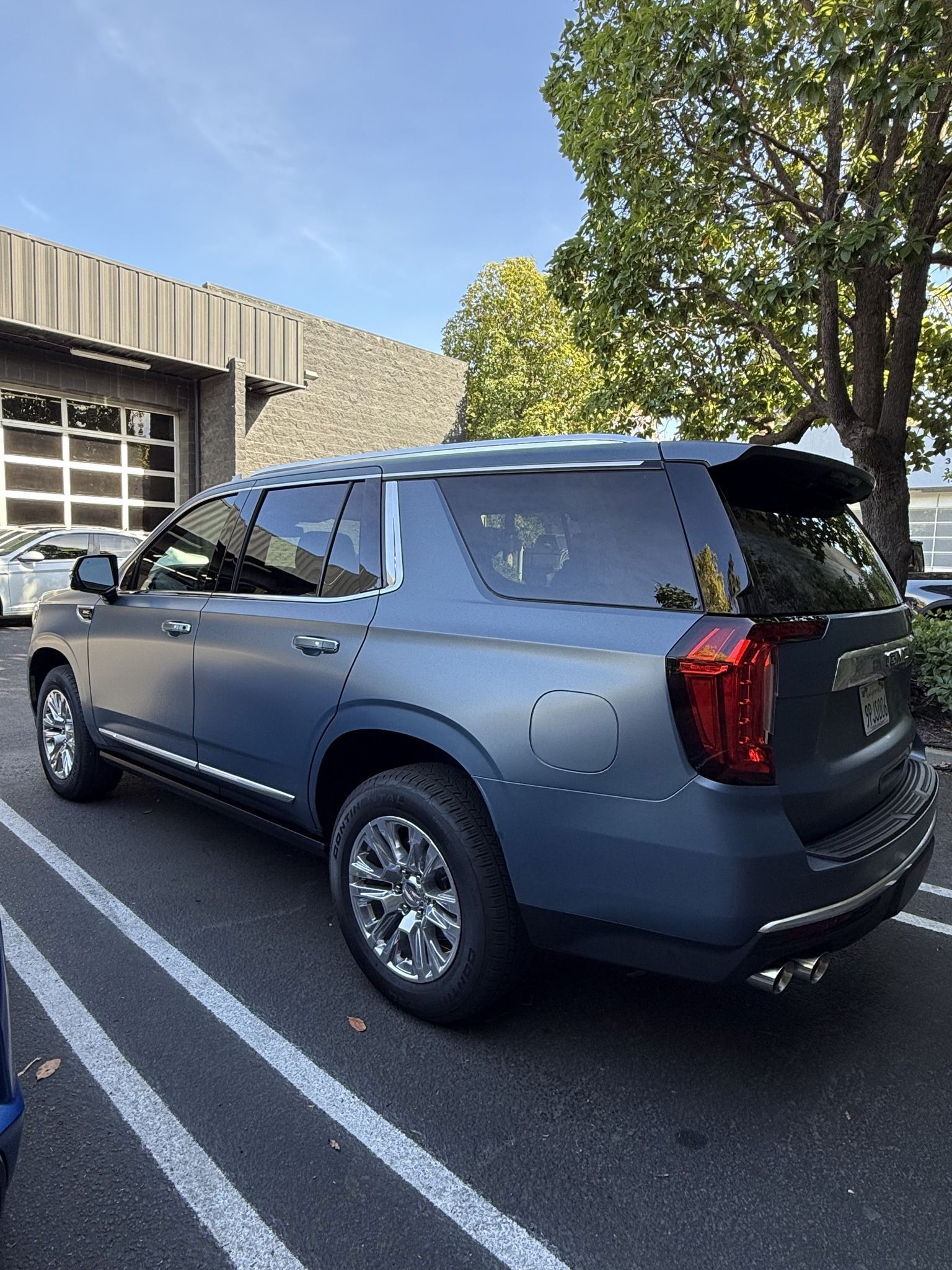 Gray SUV parked in a lot beside a building, viewed from the rear side.