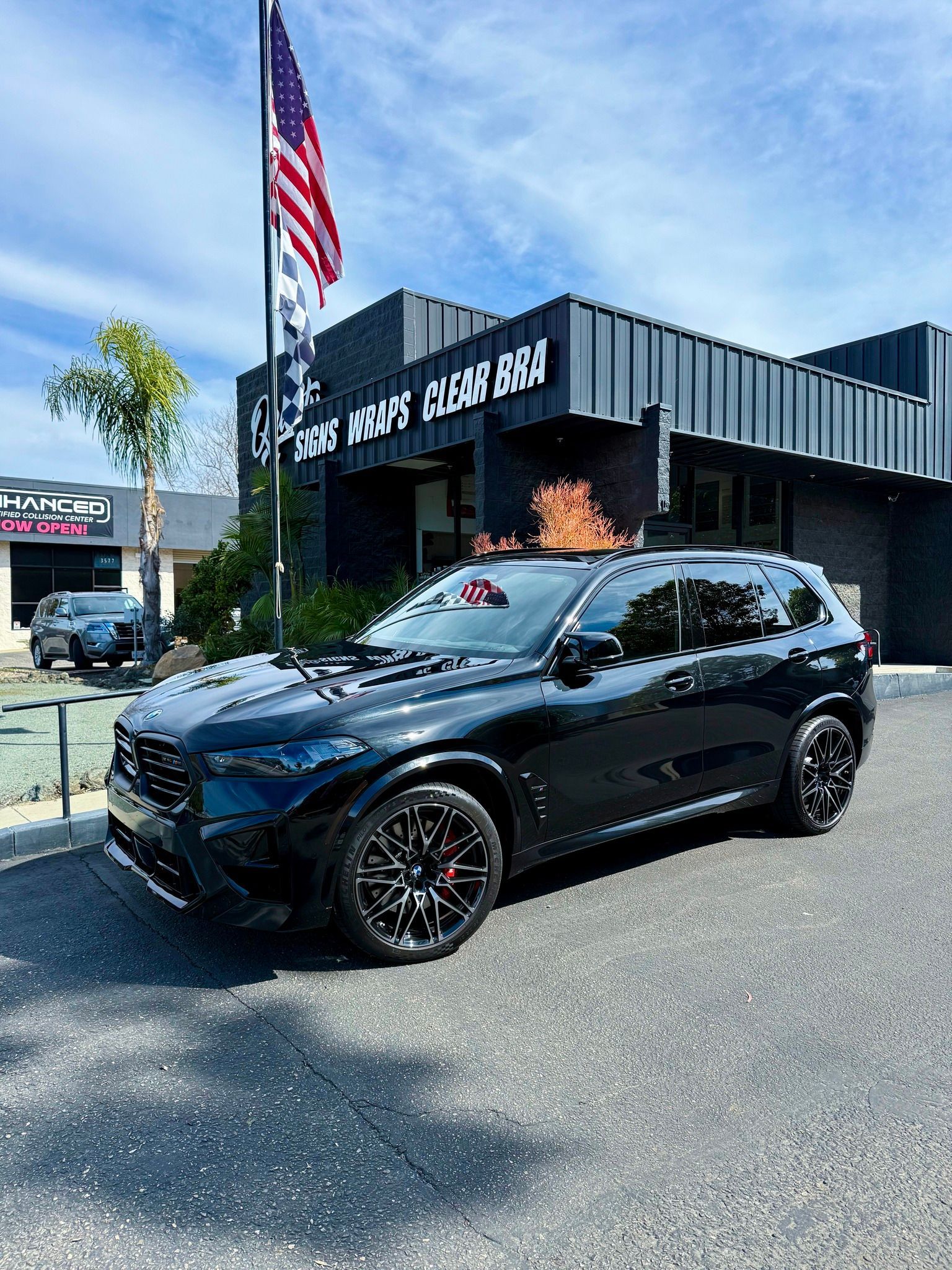 Black SUV parked outside a car wash with an American flag flying overhead.