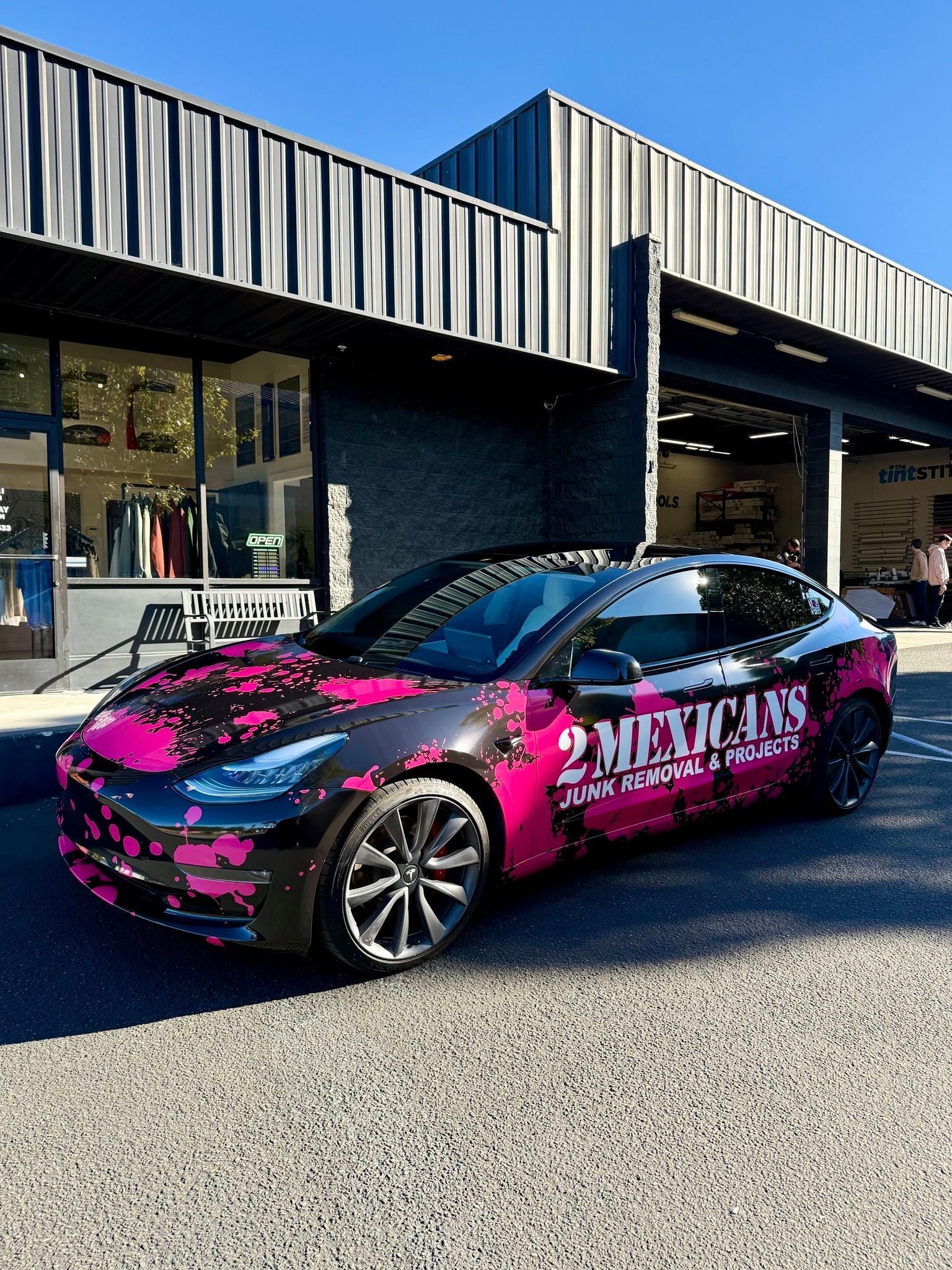 Pink-and-black wrapped sports car parked outside a modern building