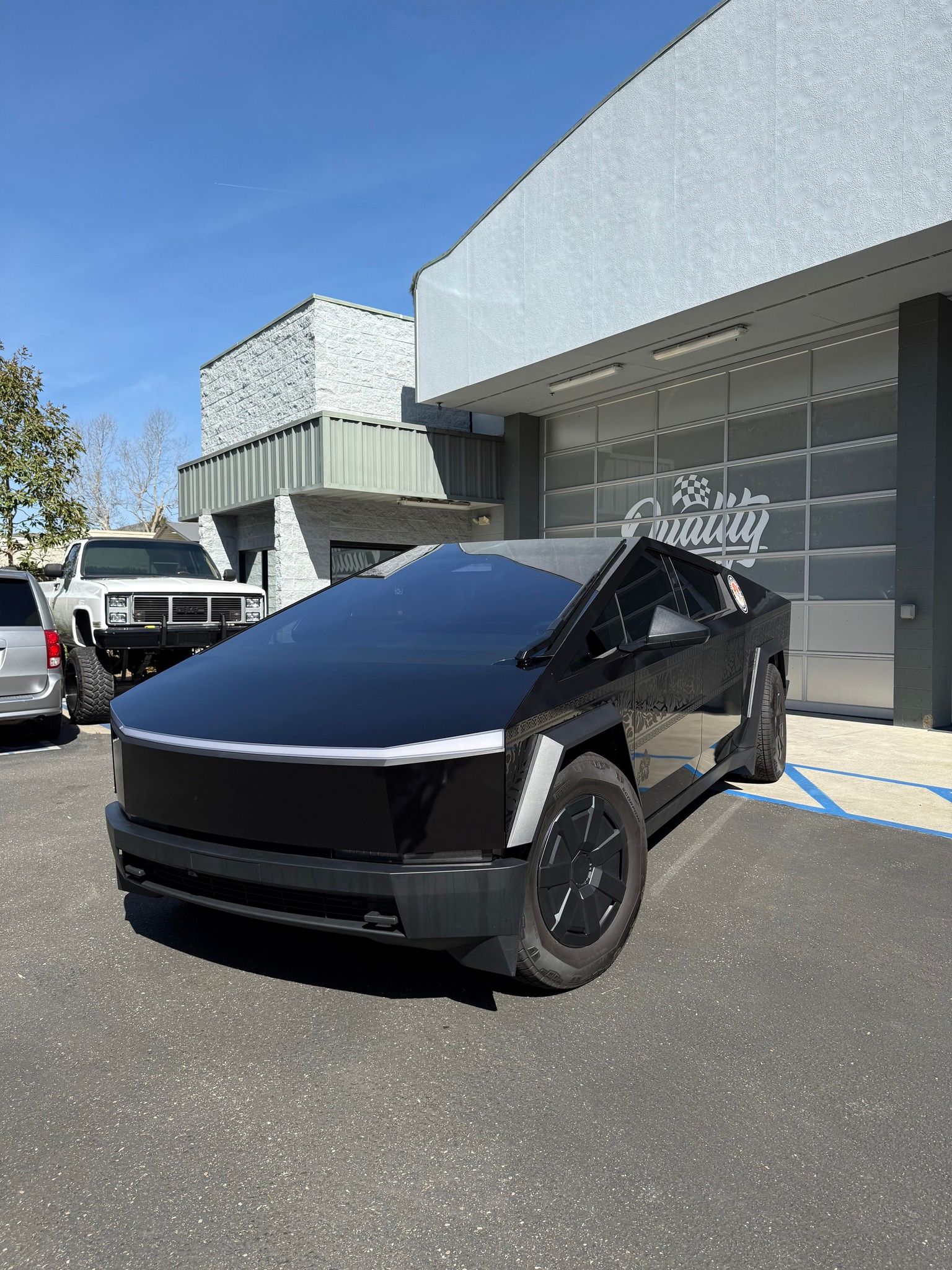 Black Tesla Cybertruck parked outside a modern building on a sunny day