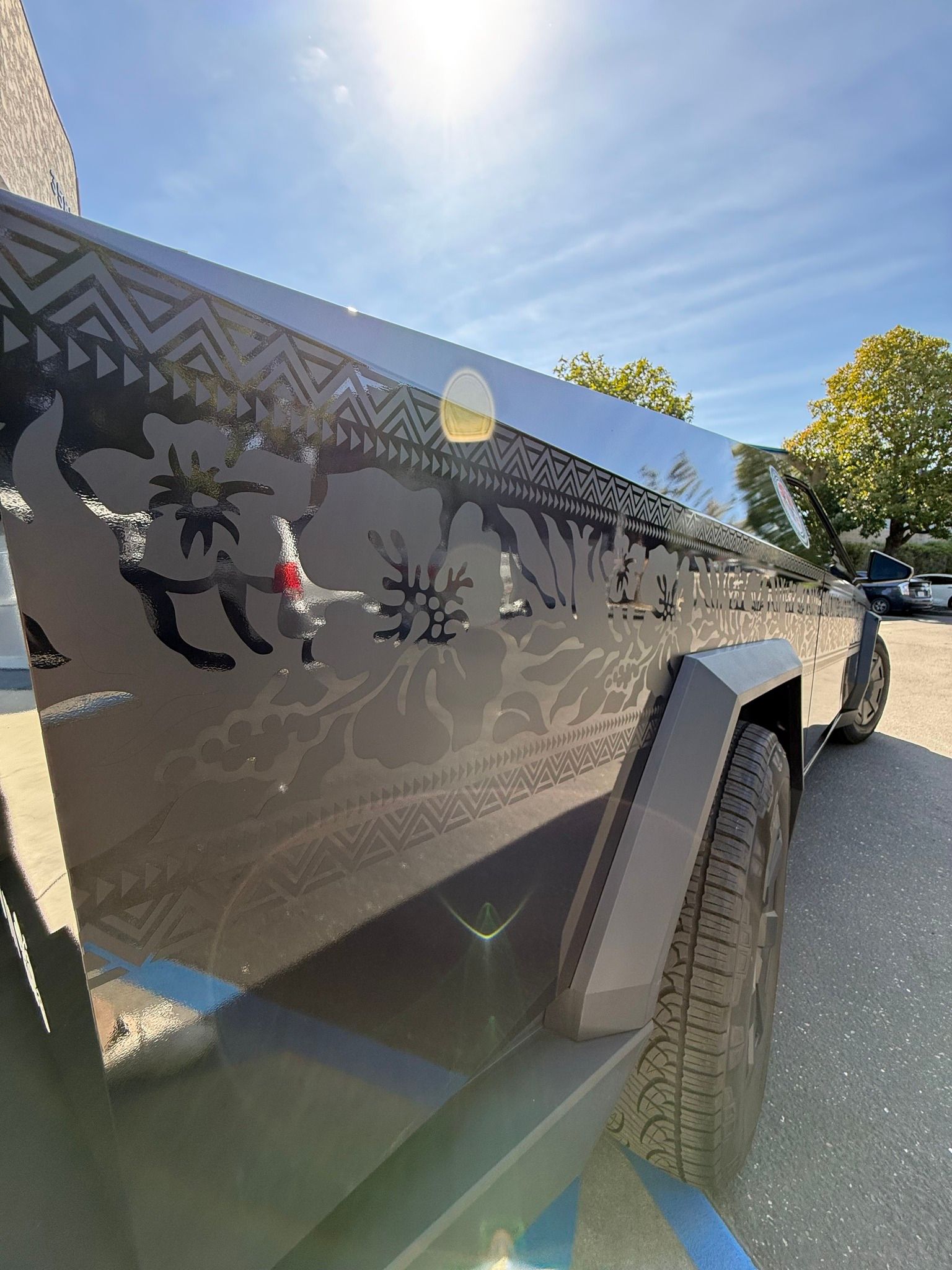 Black vehicle with reflective deer and tree decal parked outdoors in bright sun