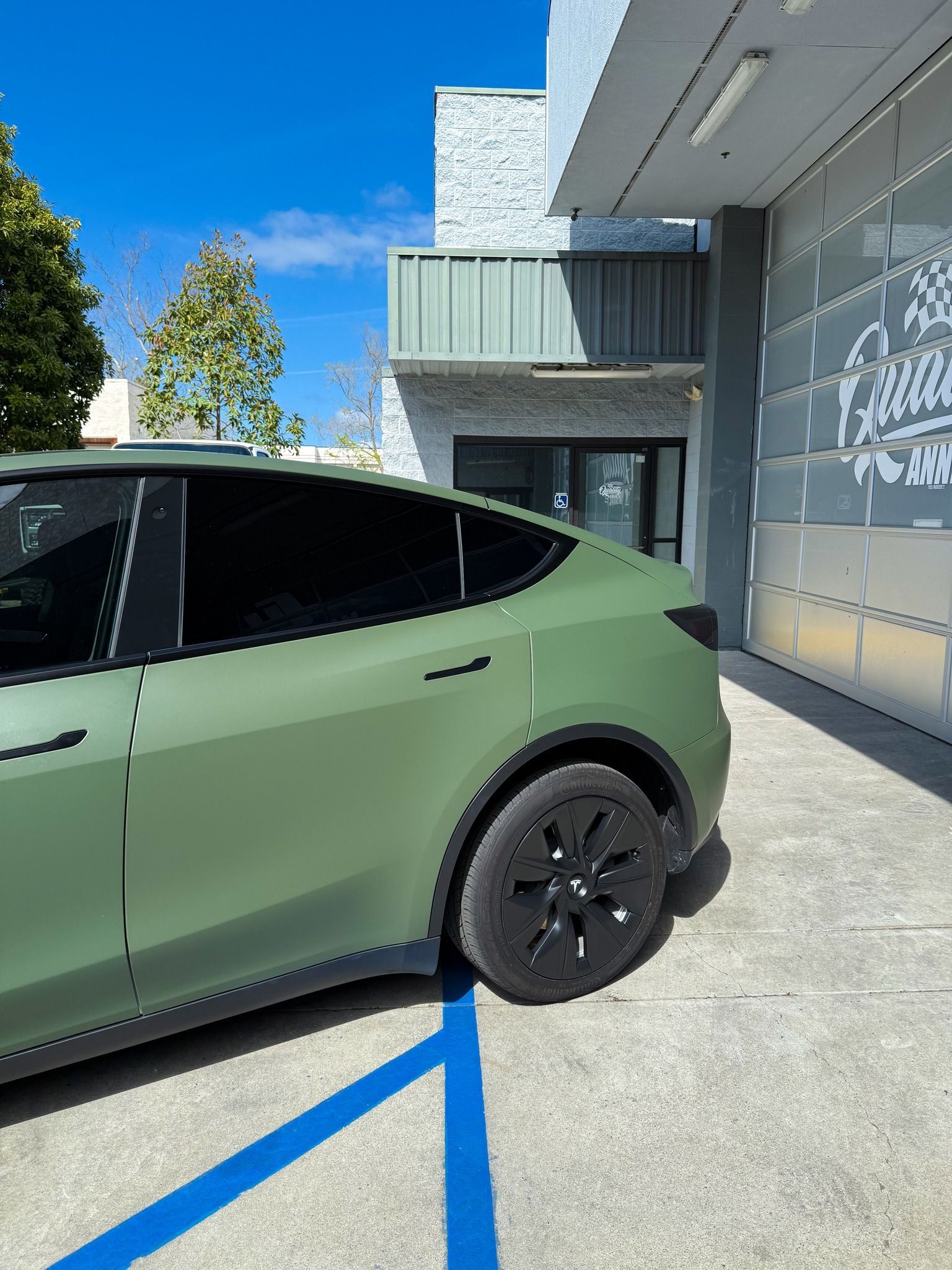 Green SUV parked beside a modern building in a marked accessible parking space.