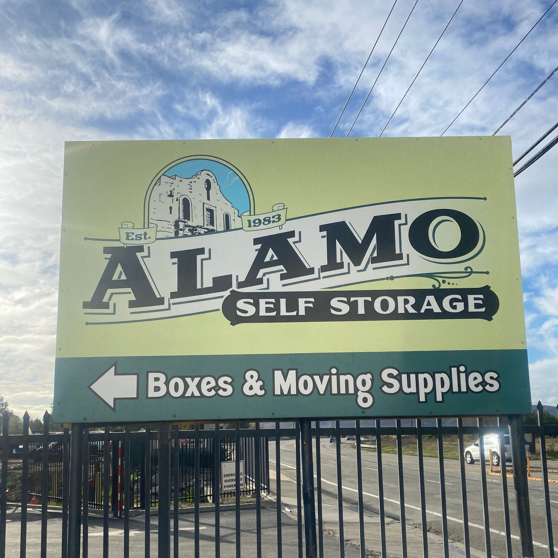 Alamo Self Storage sign with arrow for boxes and moving supplies, under a blue sky