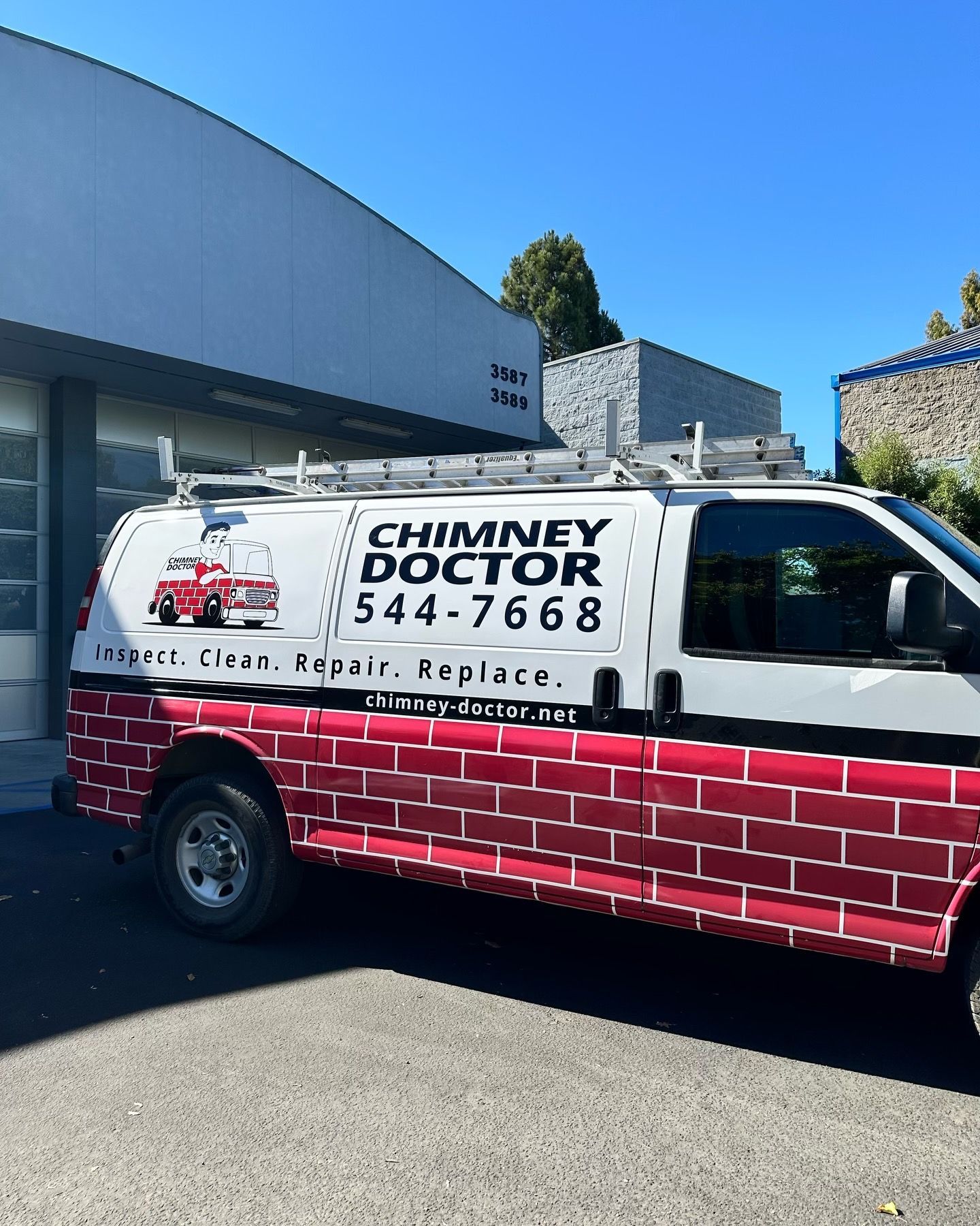 White Chimney Doctor service van with red brick graphic parked outside a building.