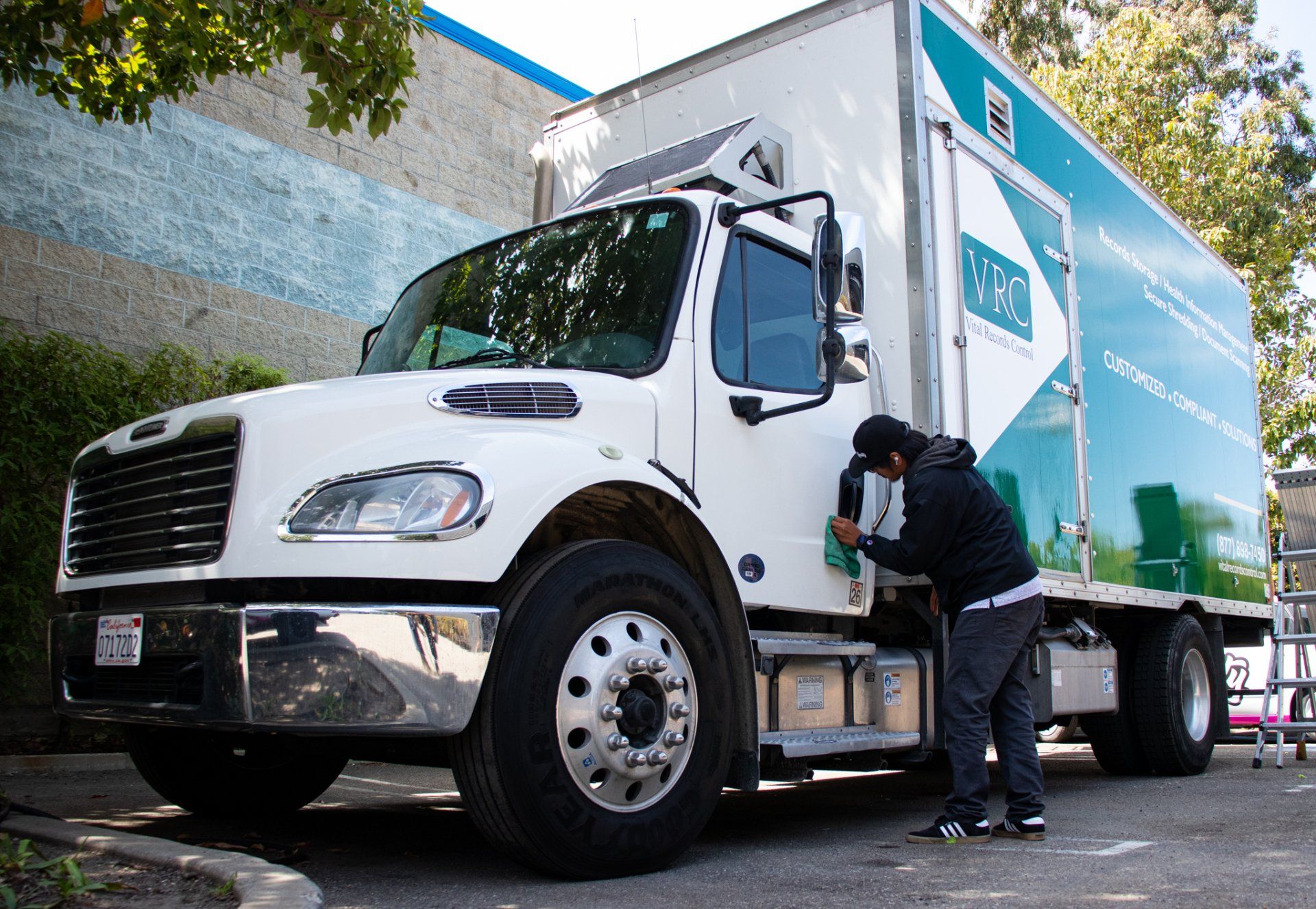 White delivery truck with a worker loading or checking items at the side door in a parking lot