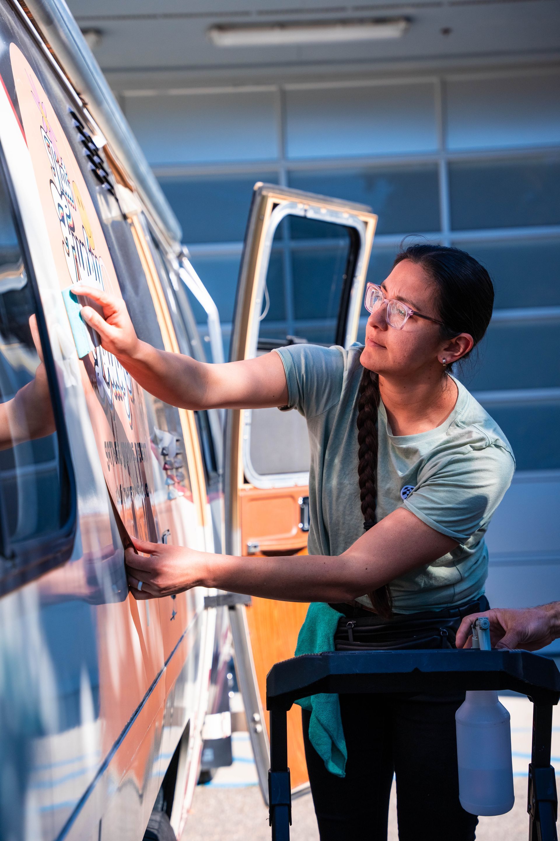 Person washing a blue-and-white van window at a car wash