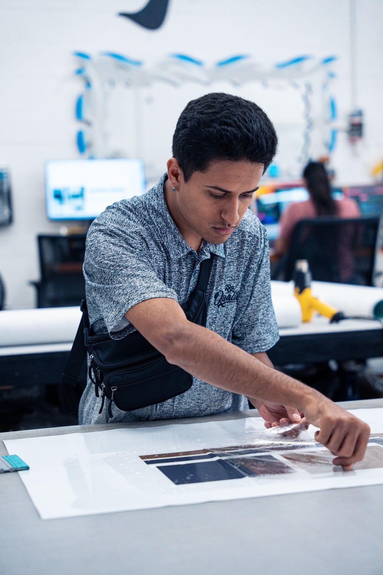 Person working with a large print at a design table in a bright studio