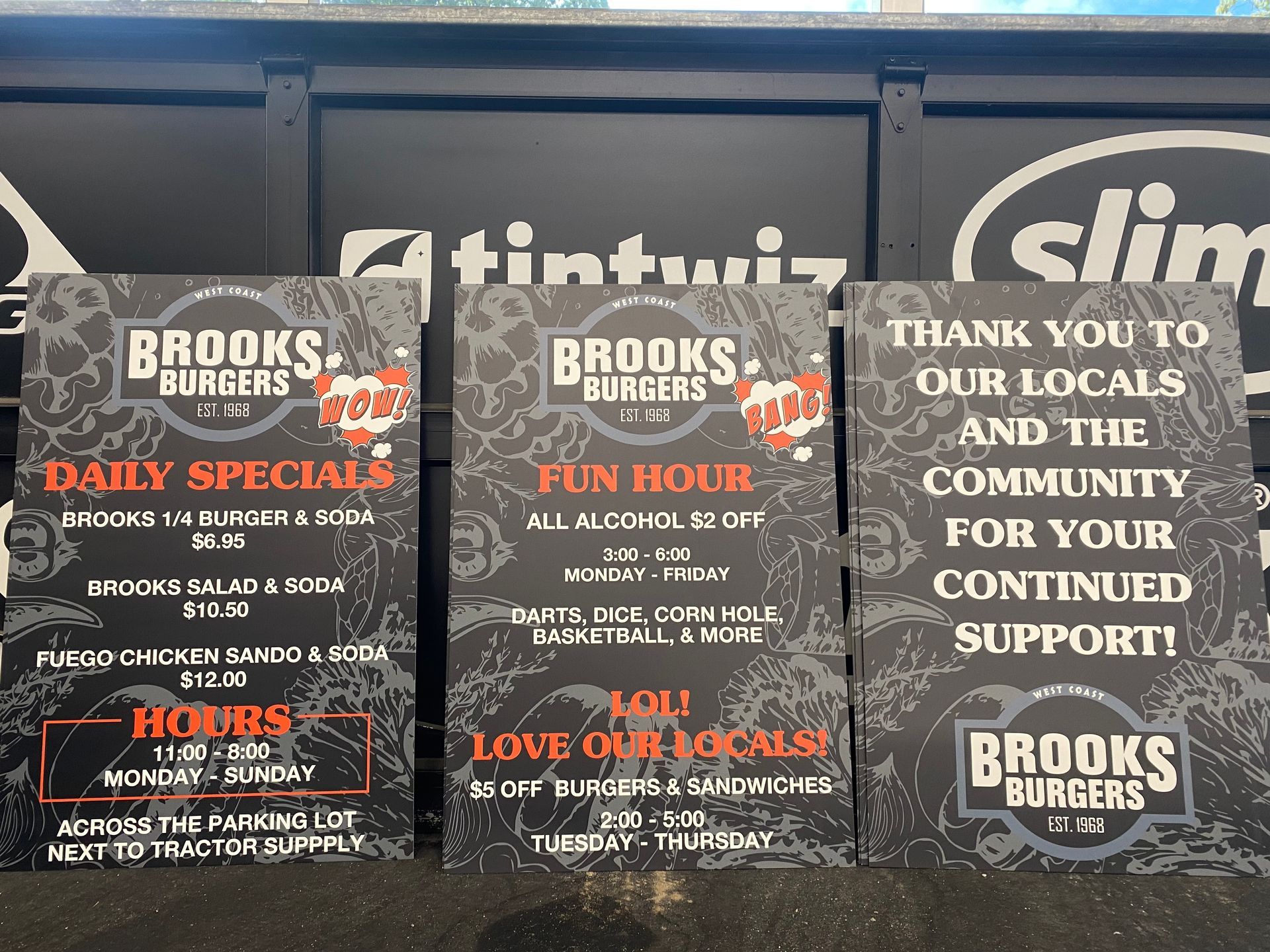 Three Brooks banners on a sidewalk, promoting specials and thanking locals for support.