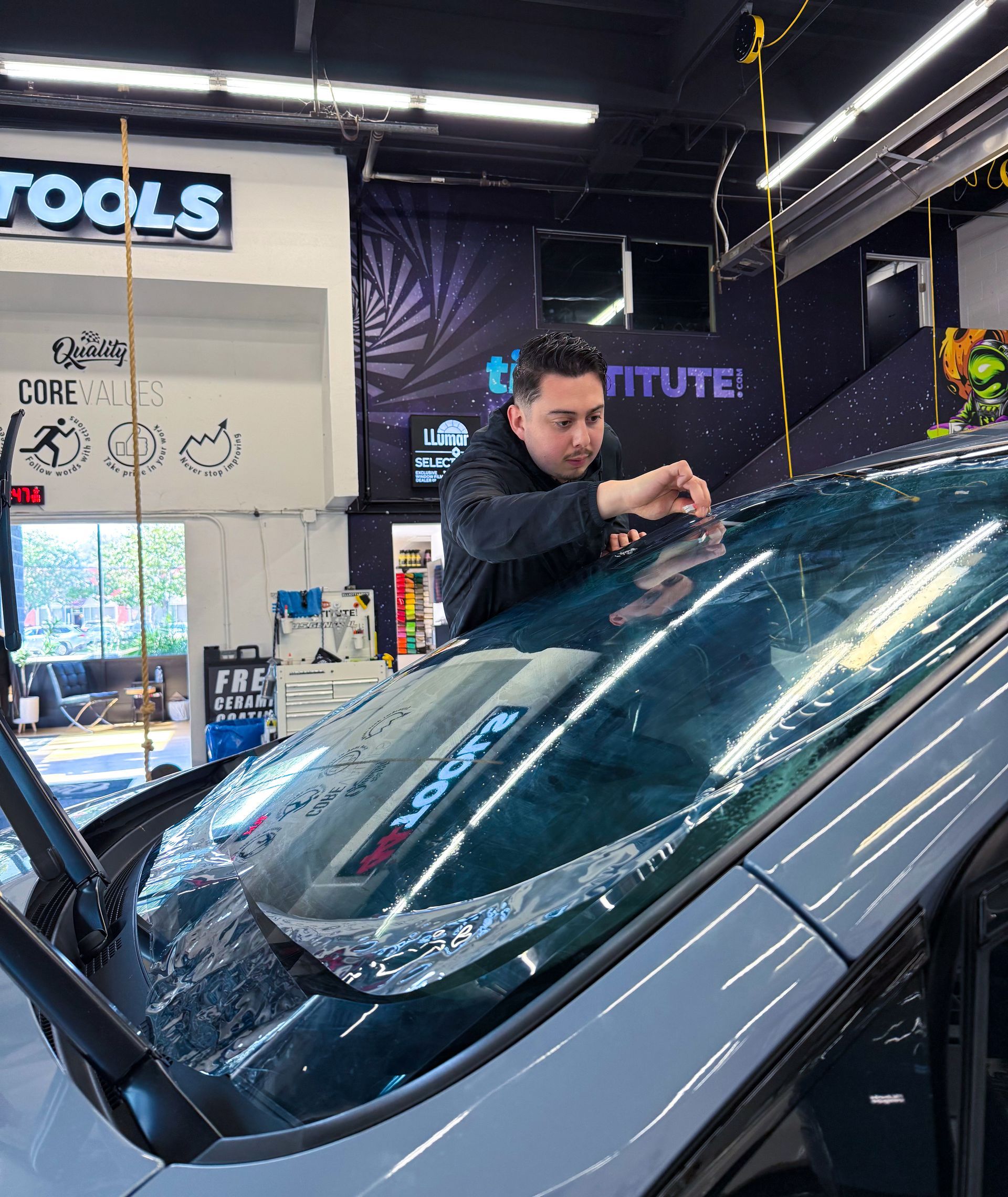 Technician polishing a car windshield in an auto shop garage