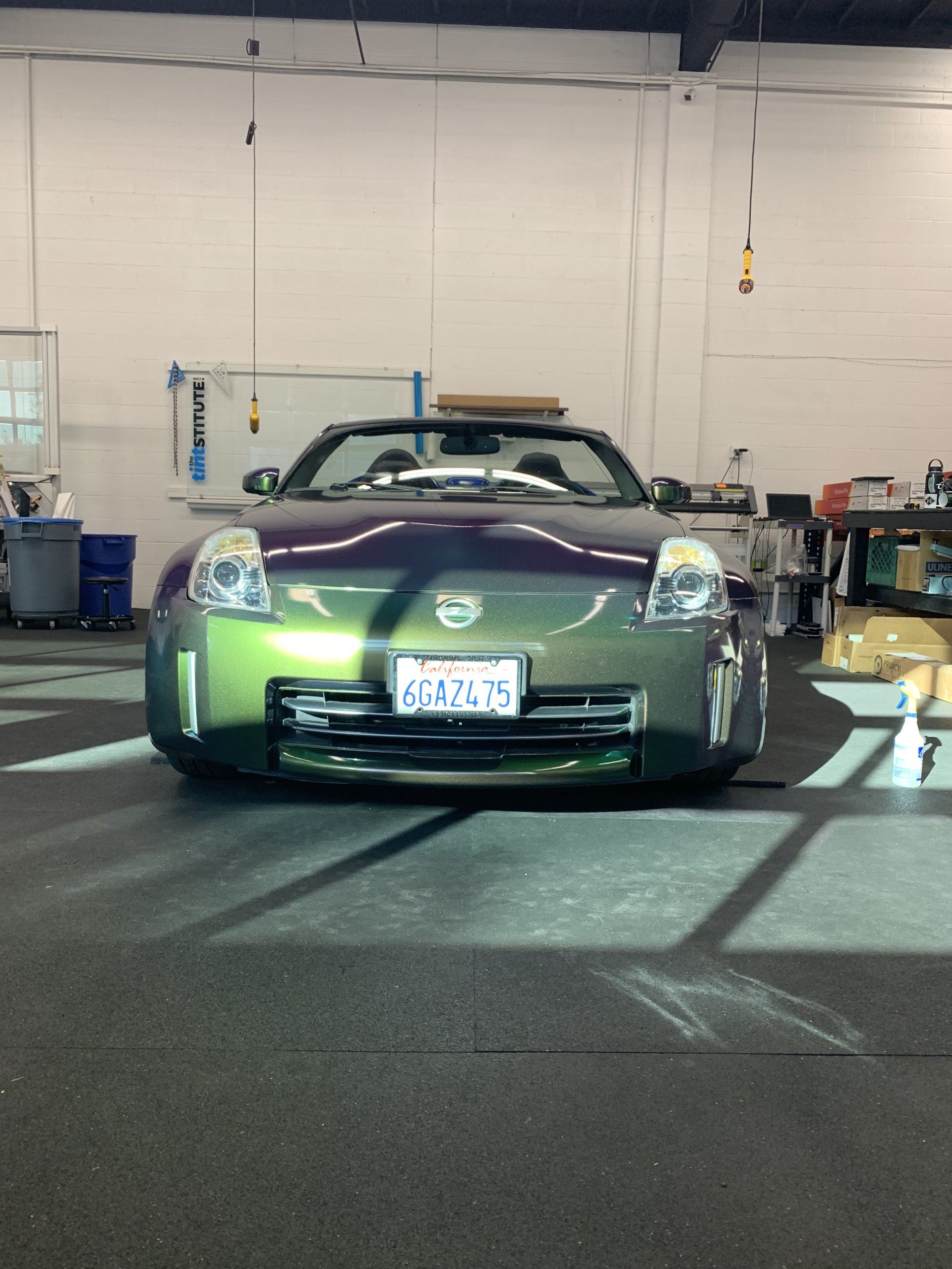 Green sports car parked indoors under bright lights, front view in a garage.