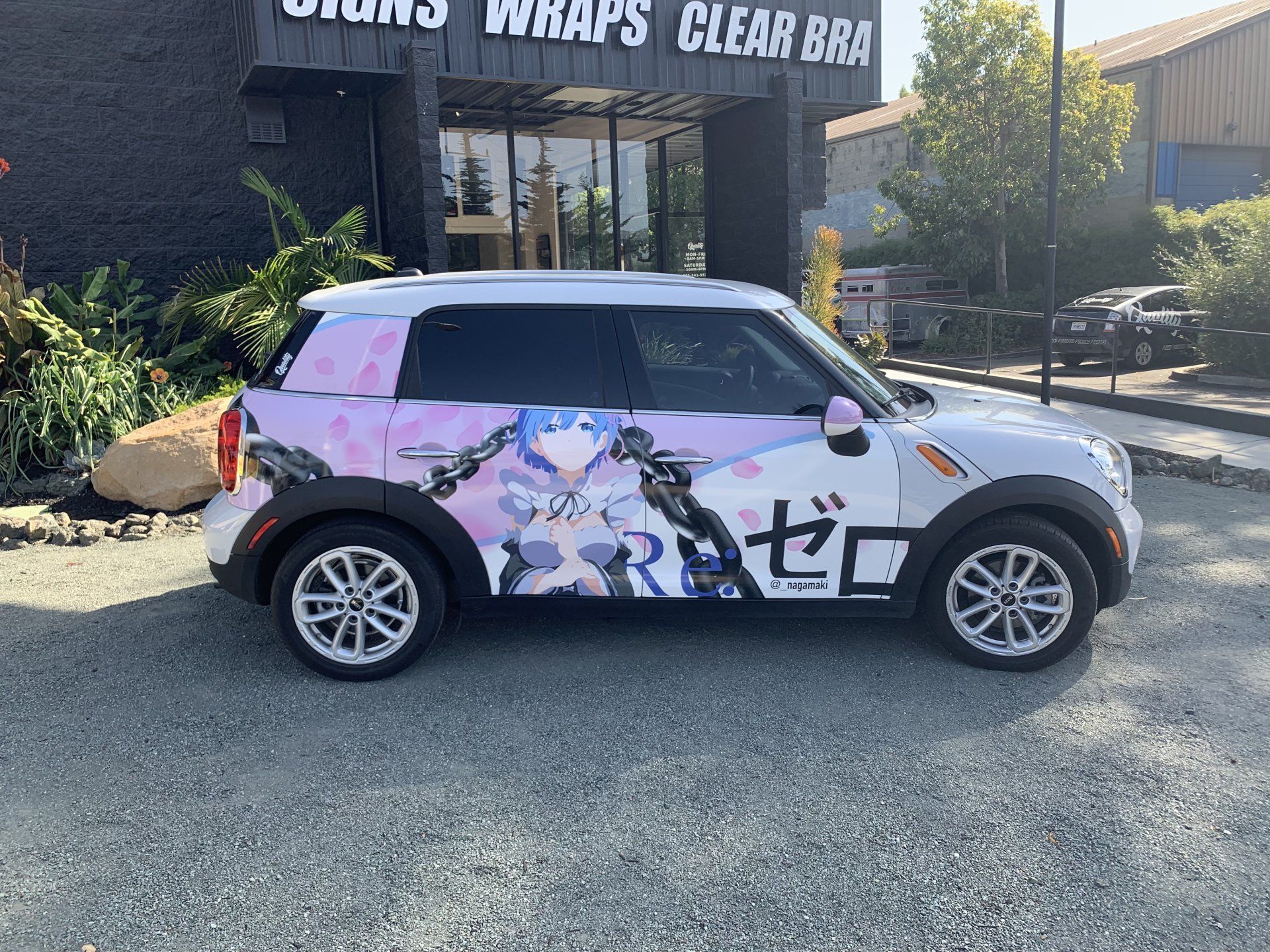Anime-wrapped white SUV parked outside a wrap shop with signs for wraps, signs, and clear bra.