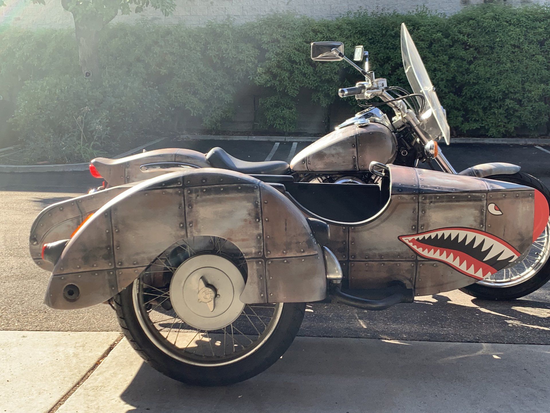 Custom sidecar motorcycle painted like a shark, parked on a sunny street.
