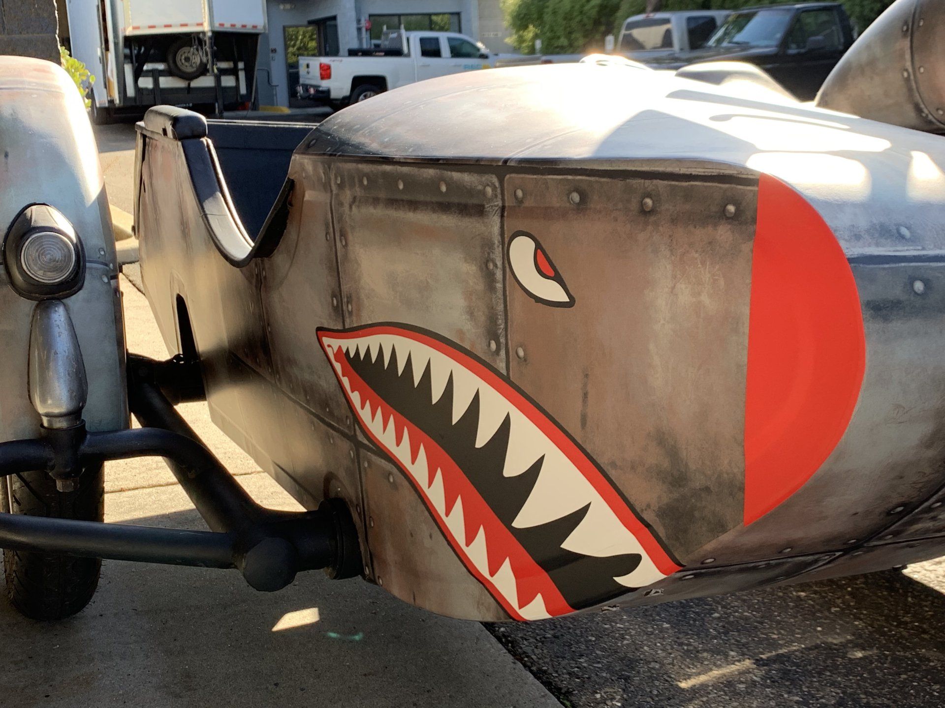 Vintage airplane nose with shark-mouth nose art and red tail marking parked outdoors