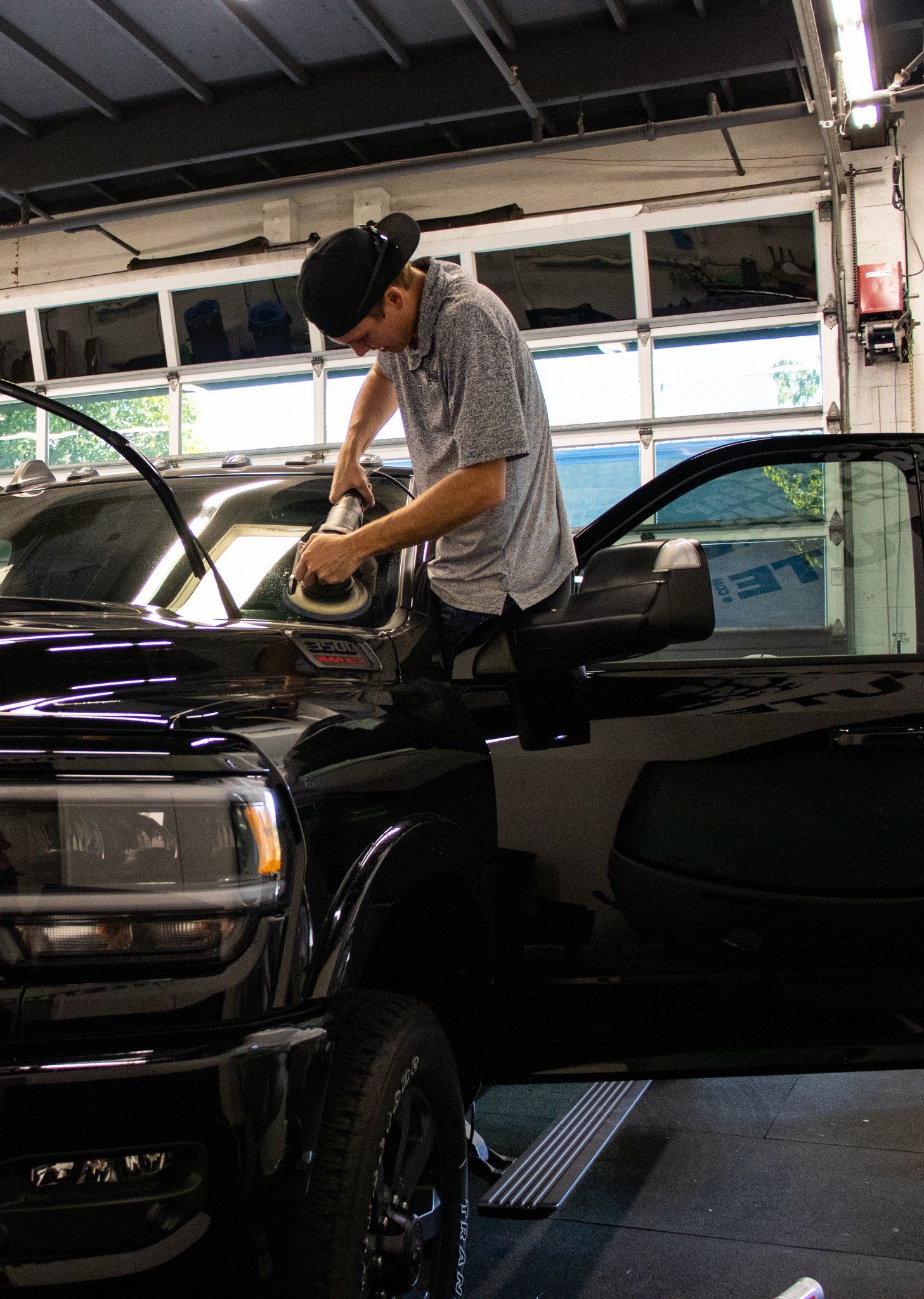 Person working on the engine of a black car inside a garage
