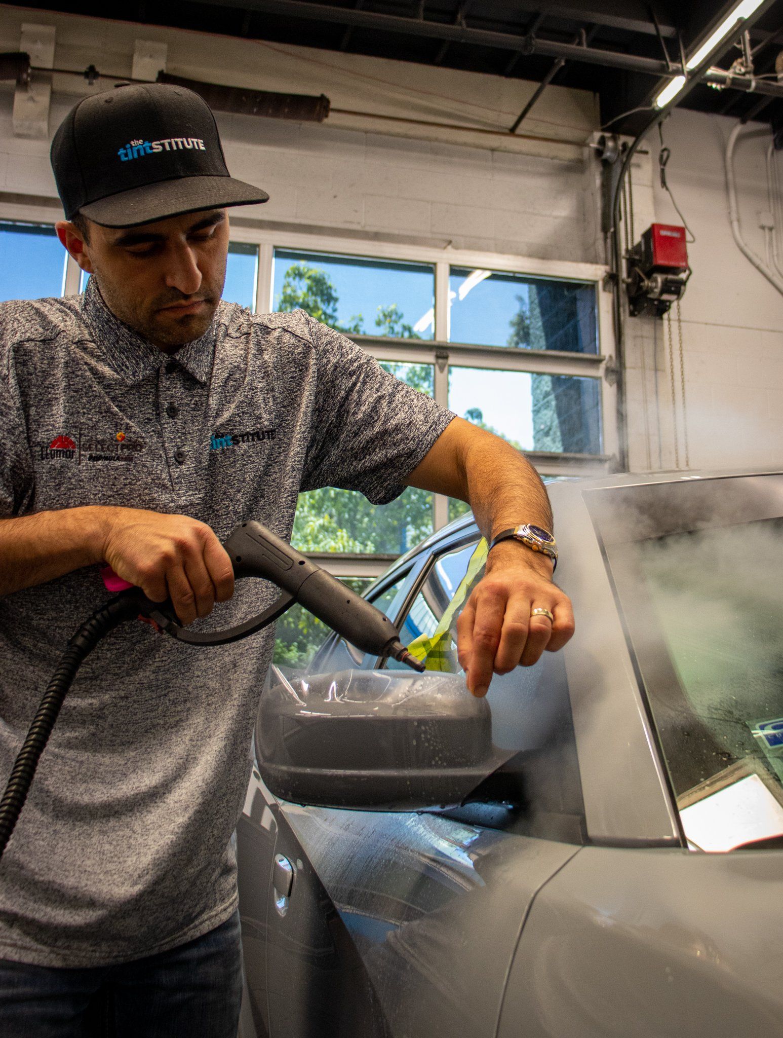 Worker using a hose to spray a metal surface in an industrial workshop.