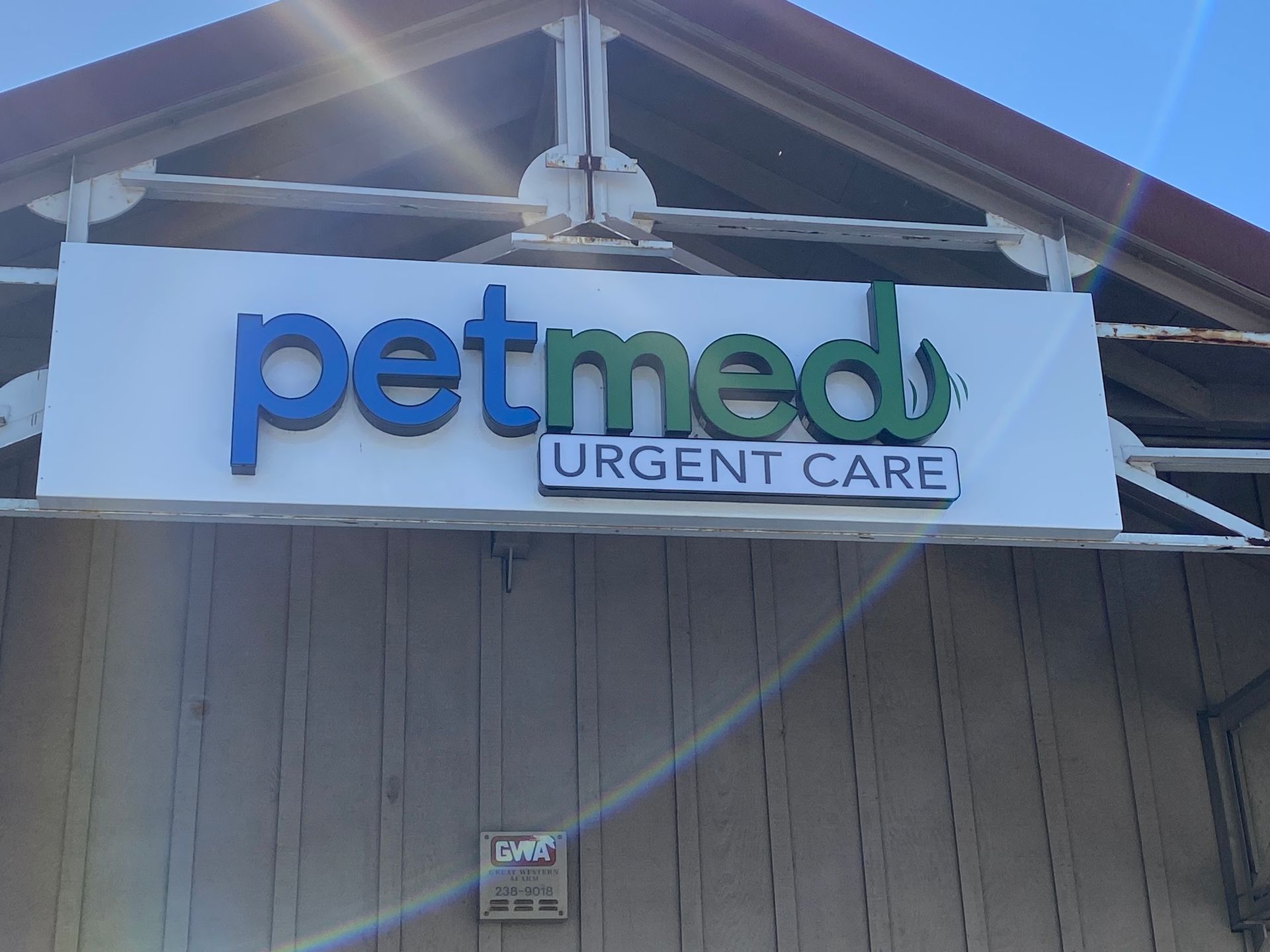 Petmed Urgent Care sign on a building exterior, with blue and green lettering.