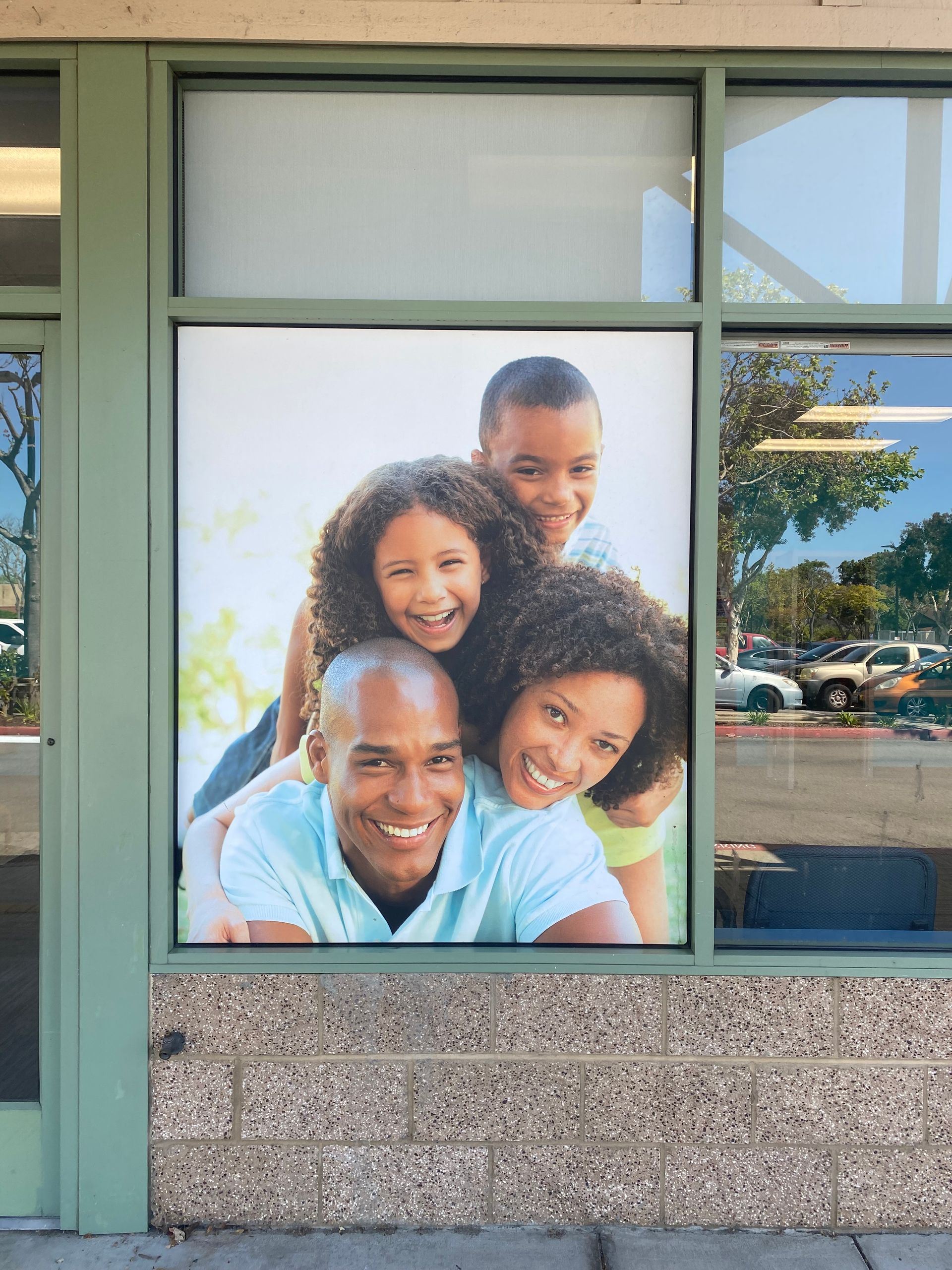 Large poster of four smiling people displayed in a storefront window