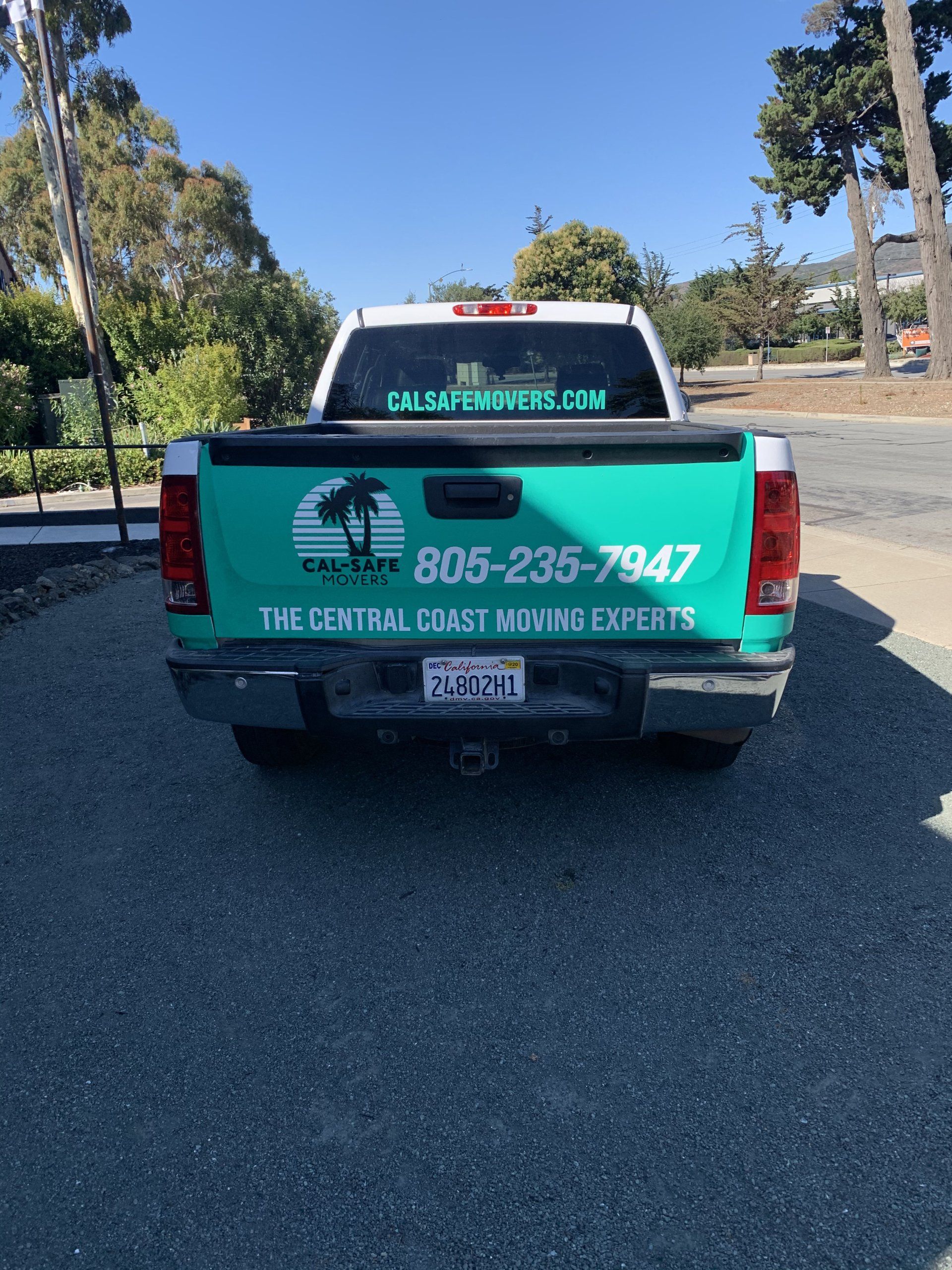 Green pickup truck with “The Central Coast House Experts” signage parked on a sunny street.