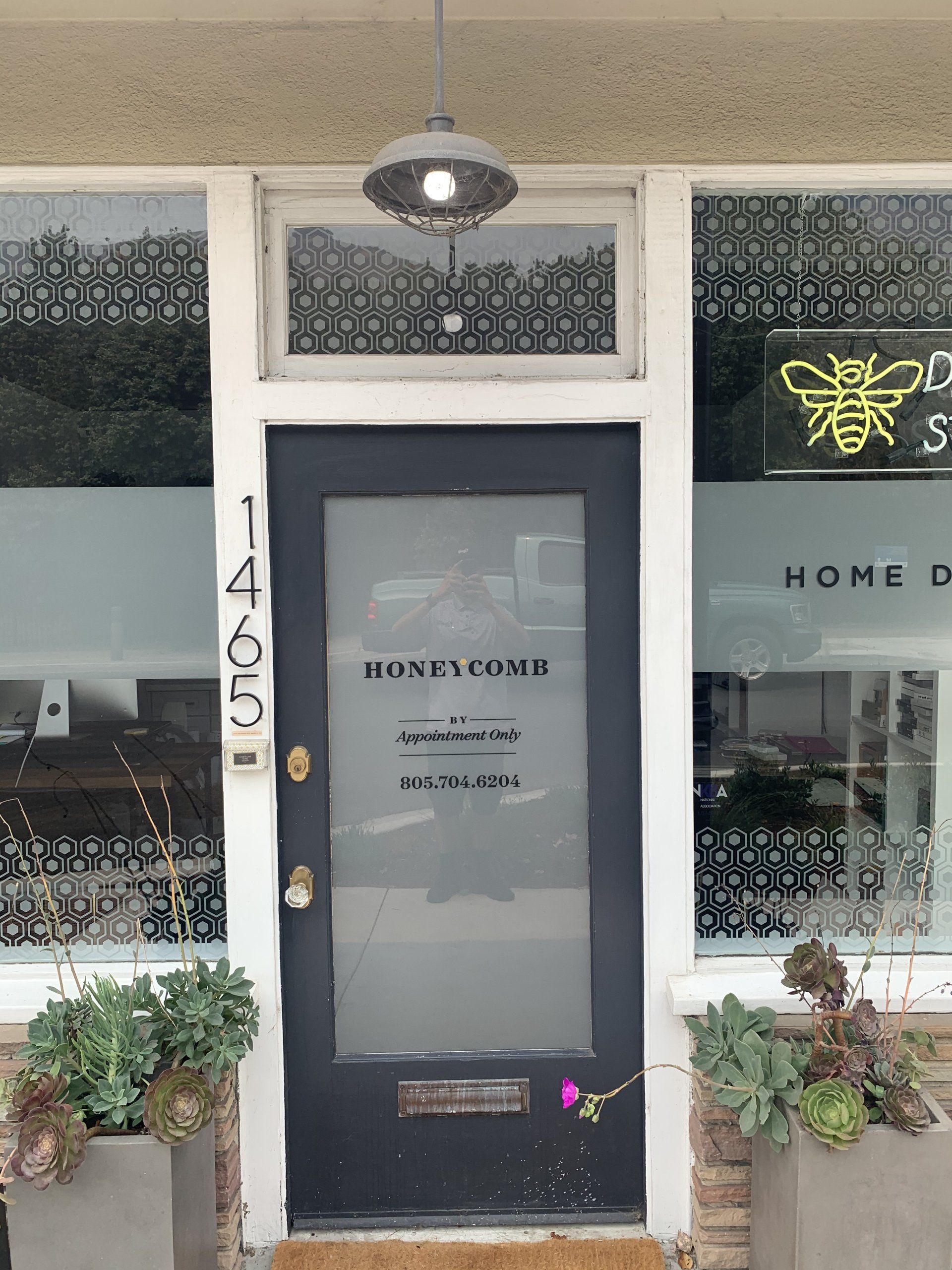 Storefront entrance with black door, frosted glass, and potted plants on either side