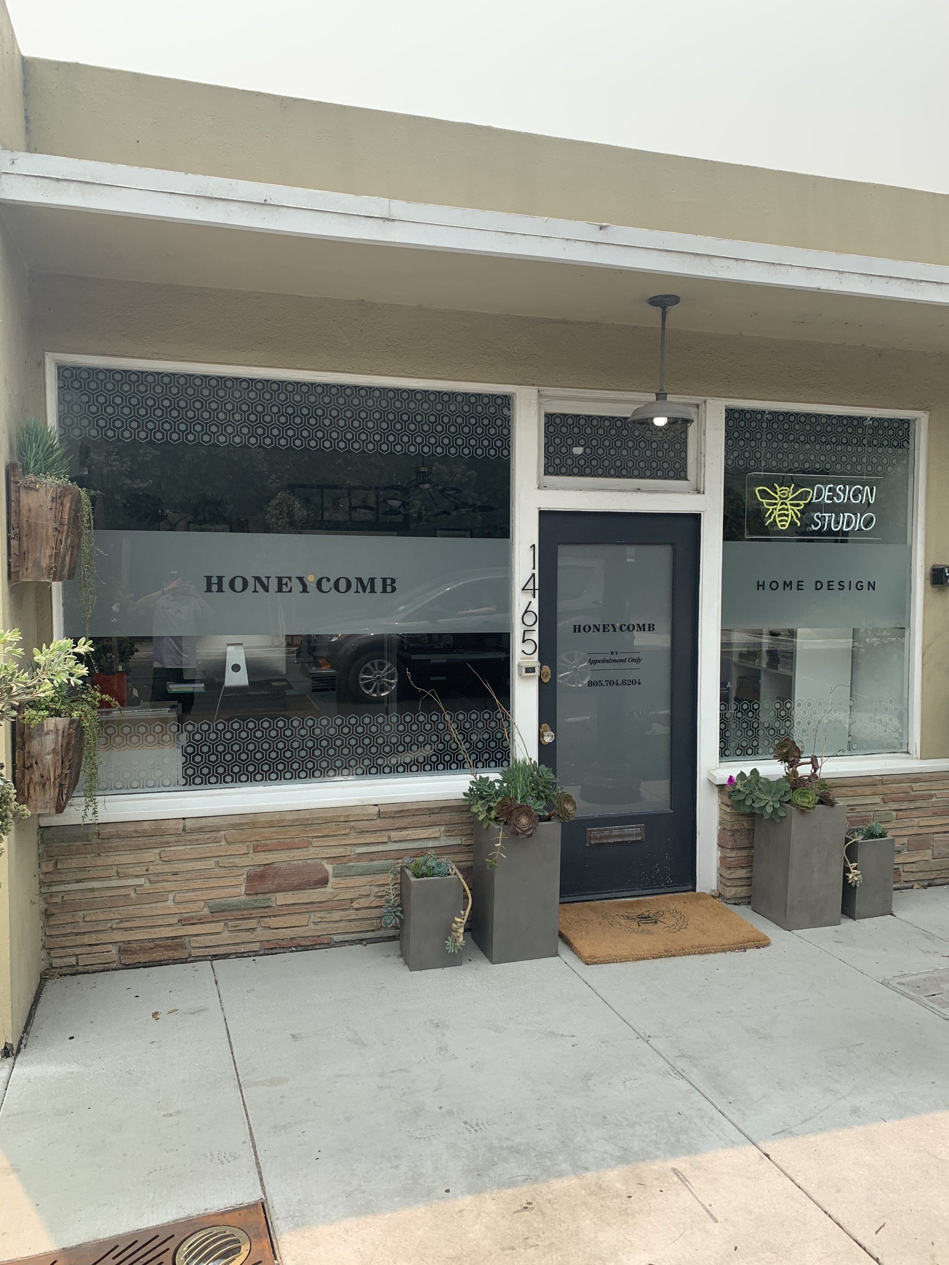 Small coffee shop storefront with a white awning, glass door, and stone-accent counter display.