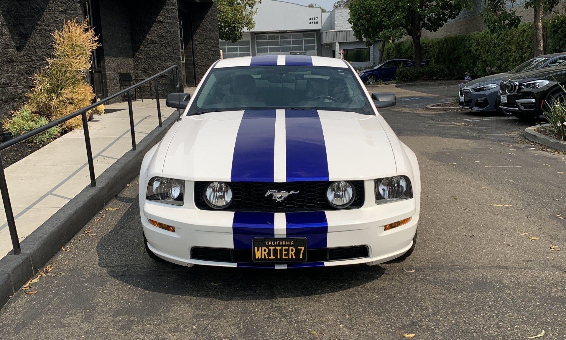 White sports car with blue racing stripes parked outdoors in a lot